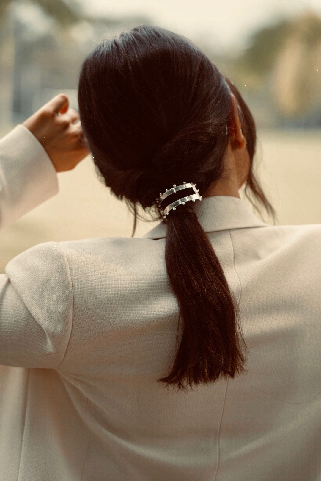 demoiselle d'honneur le jour du mariage avec blazer blanc coiffée avec une queue de cheval bas et un élastique en argent bohème