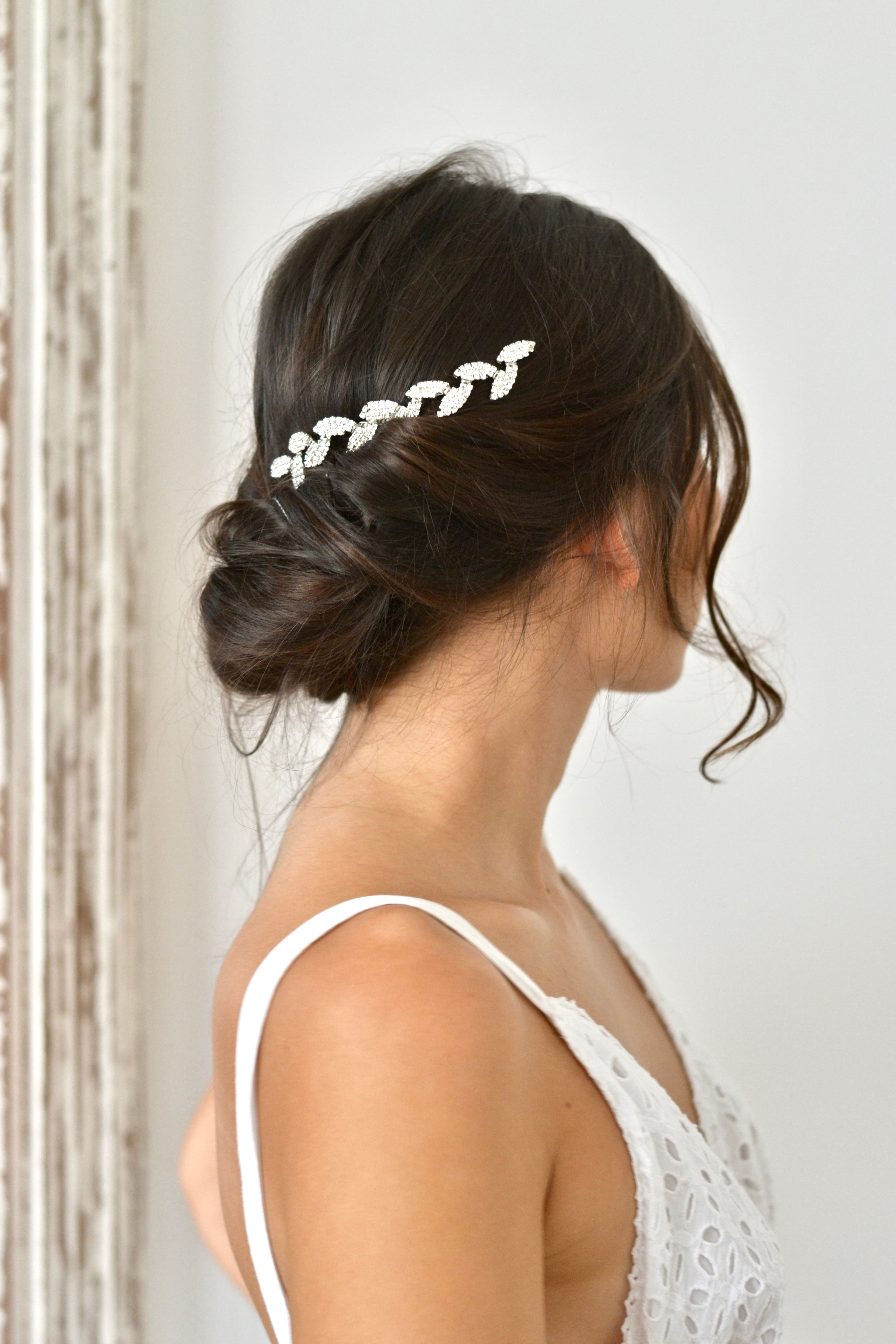 Mariée avec chignon bohème portant une vigne de cheveux en feuilles argentées et cristaux