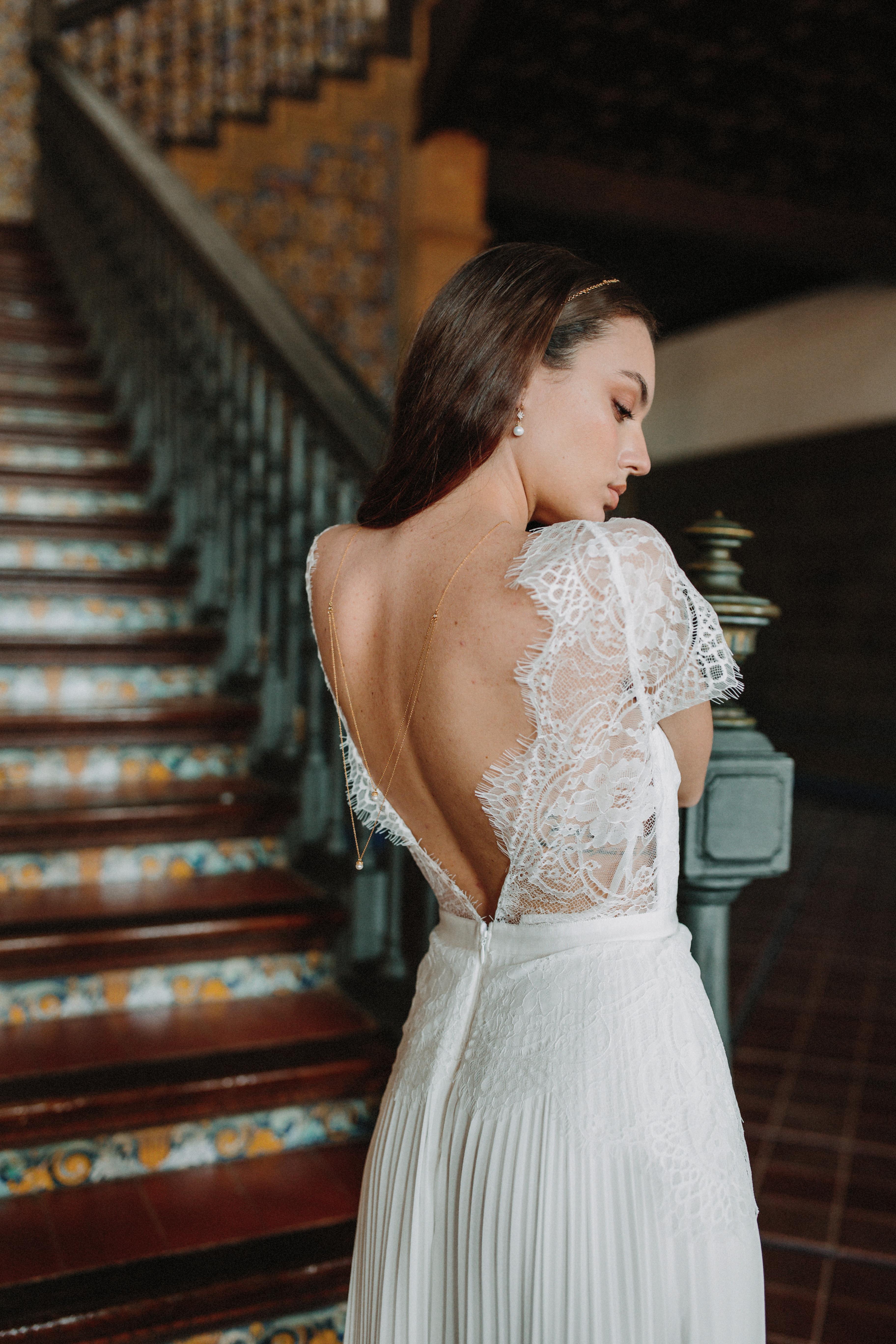 Mariée au style bohème portant un collier de dos à doubles chaînes dorées avec une perle à chaque extrémité, boucles d'oreilles assorties