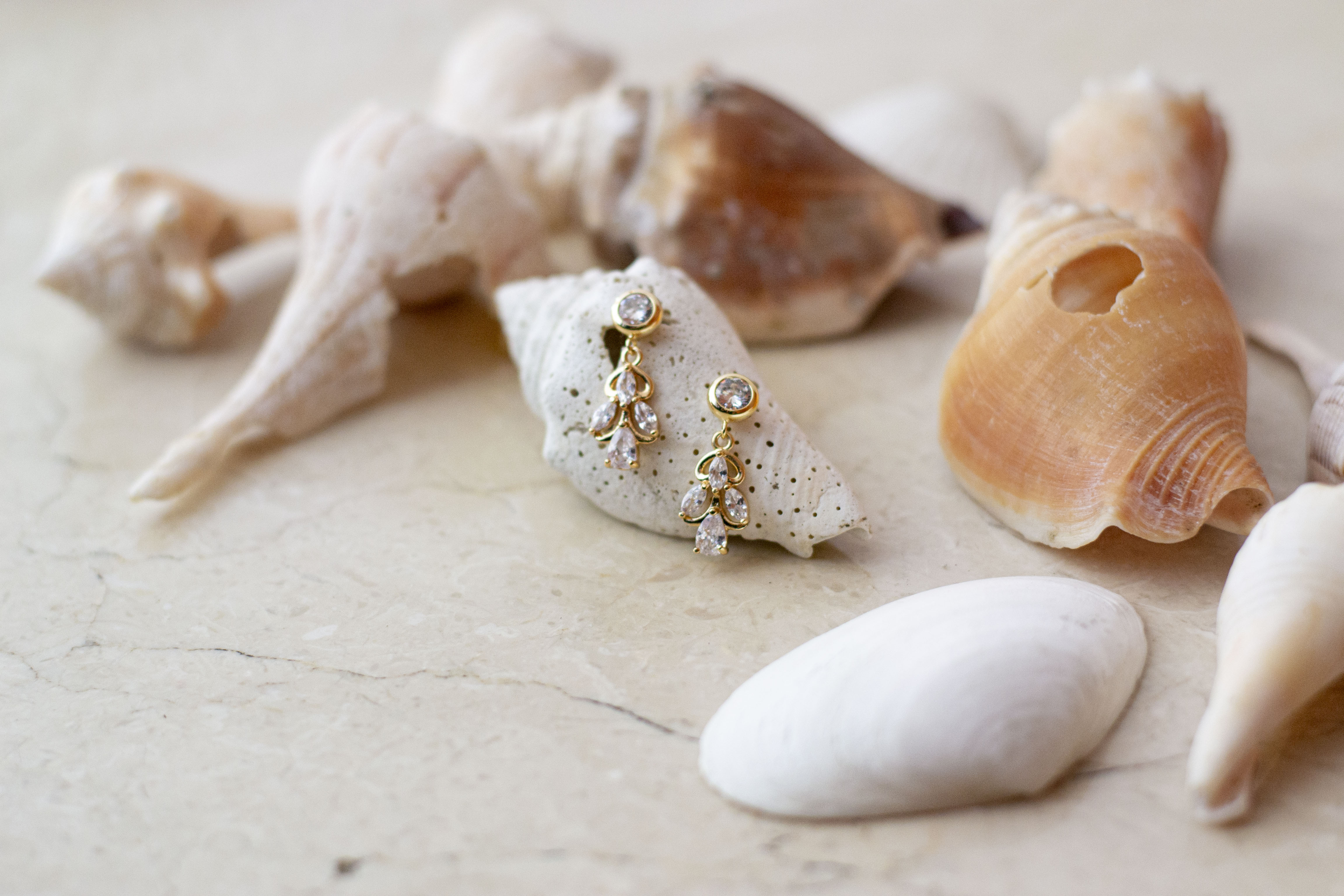 Boucles d'oreilles élégantes pendantes dorées à cristaux sur des coquillages