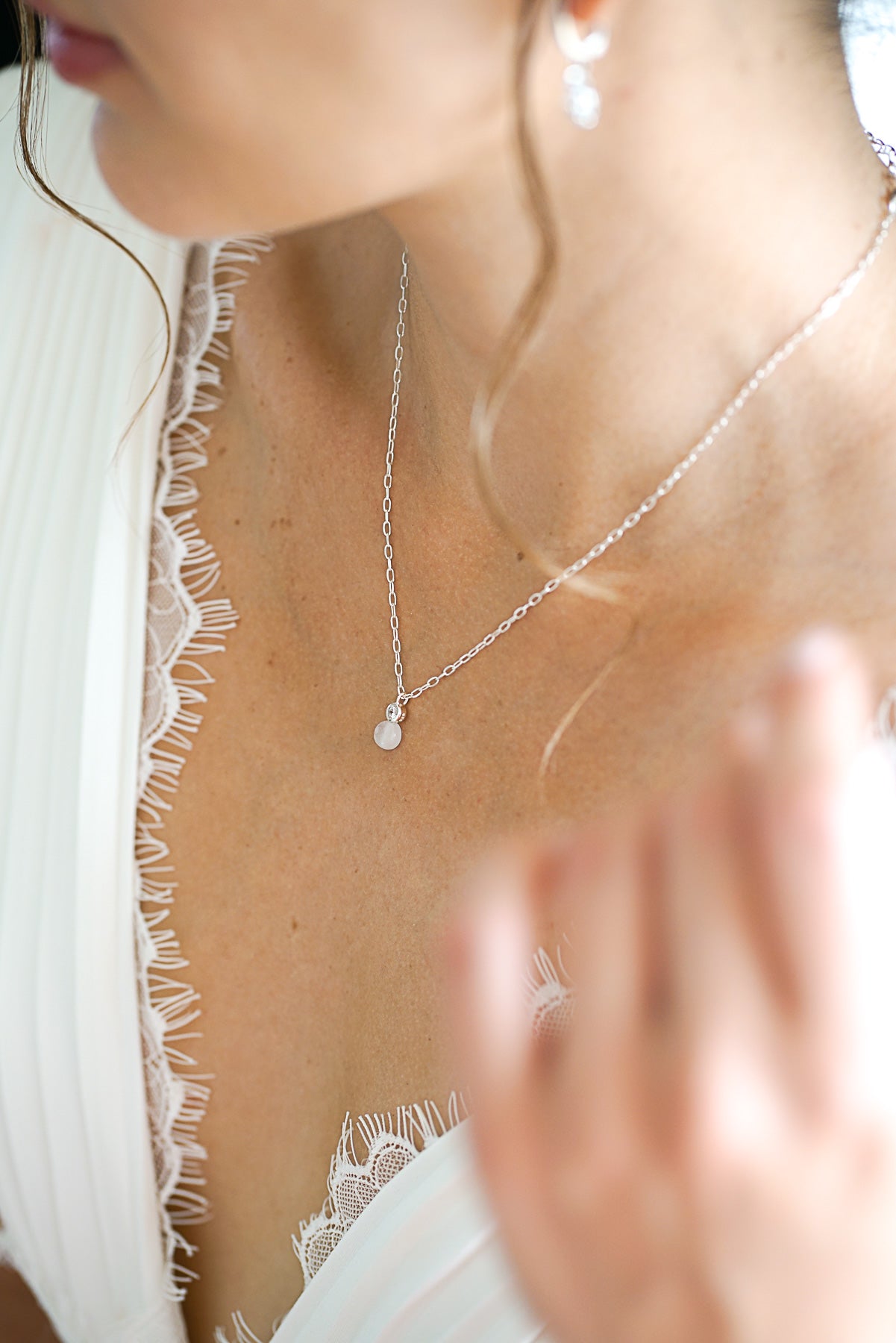 collier de mariage long porté par une mariée avec une robe blanche plissé et avec un décolleté en dentelle