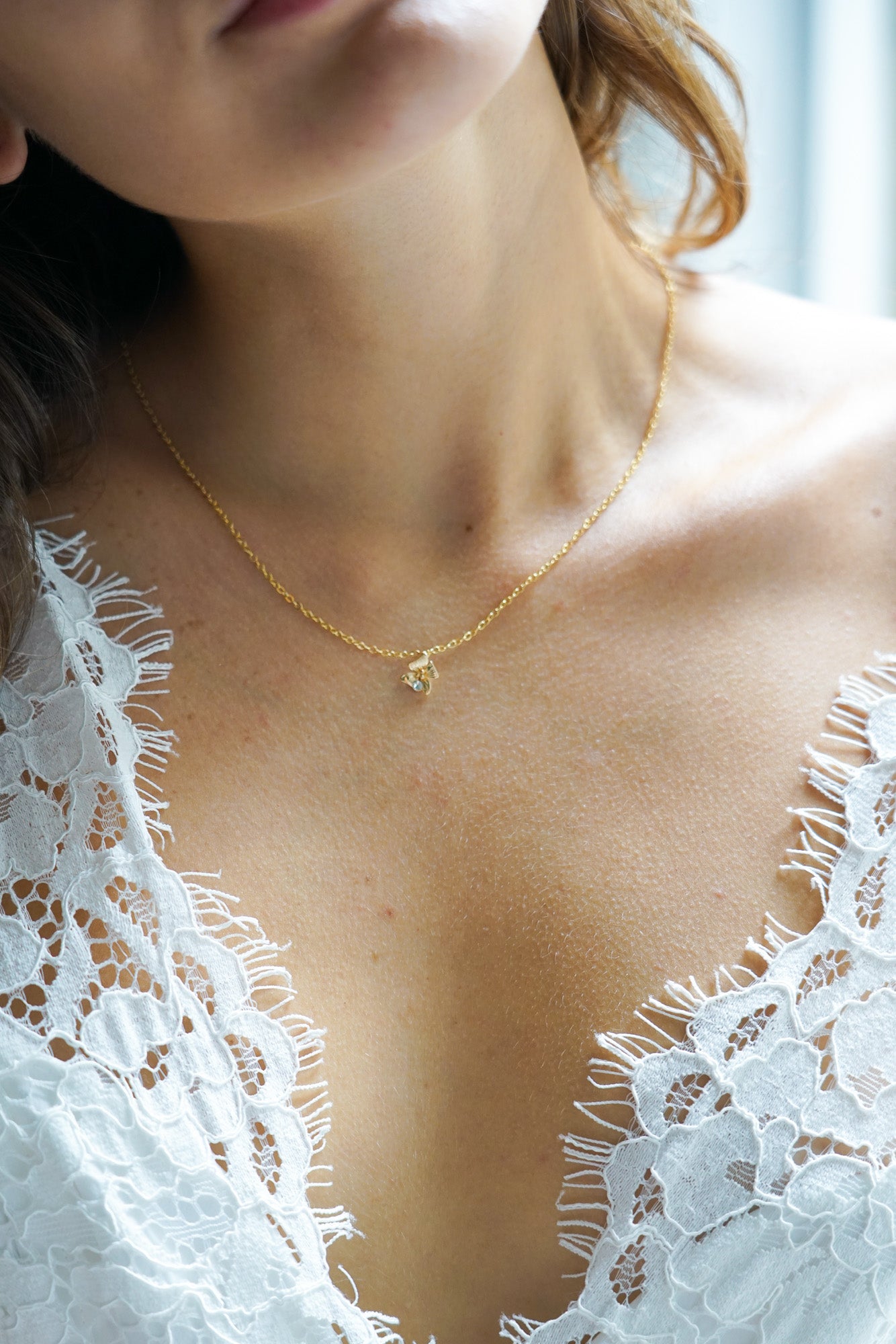 collier de mariage en or avec un pendentif porté par une mariée avec une robe de mariée