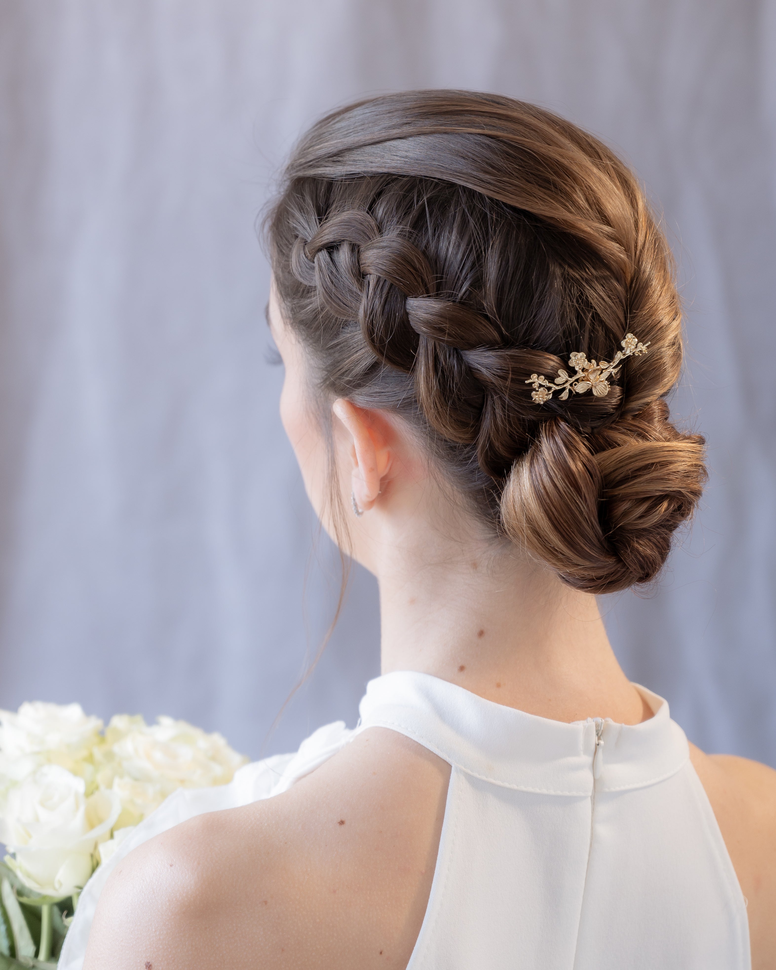 Mariée avec chignon de mariage tressé et pic à cheveux doré floral