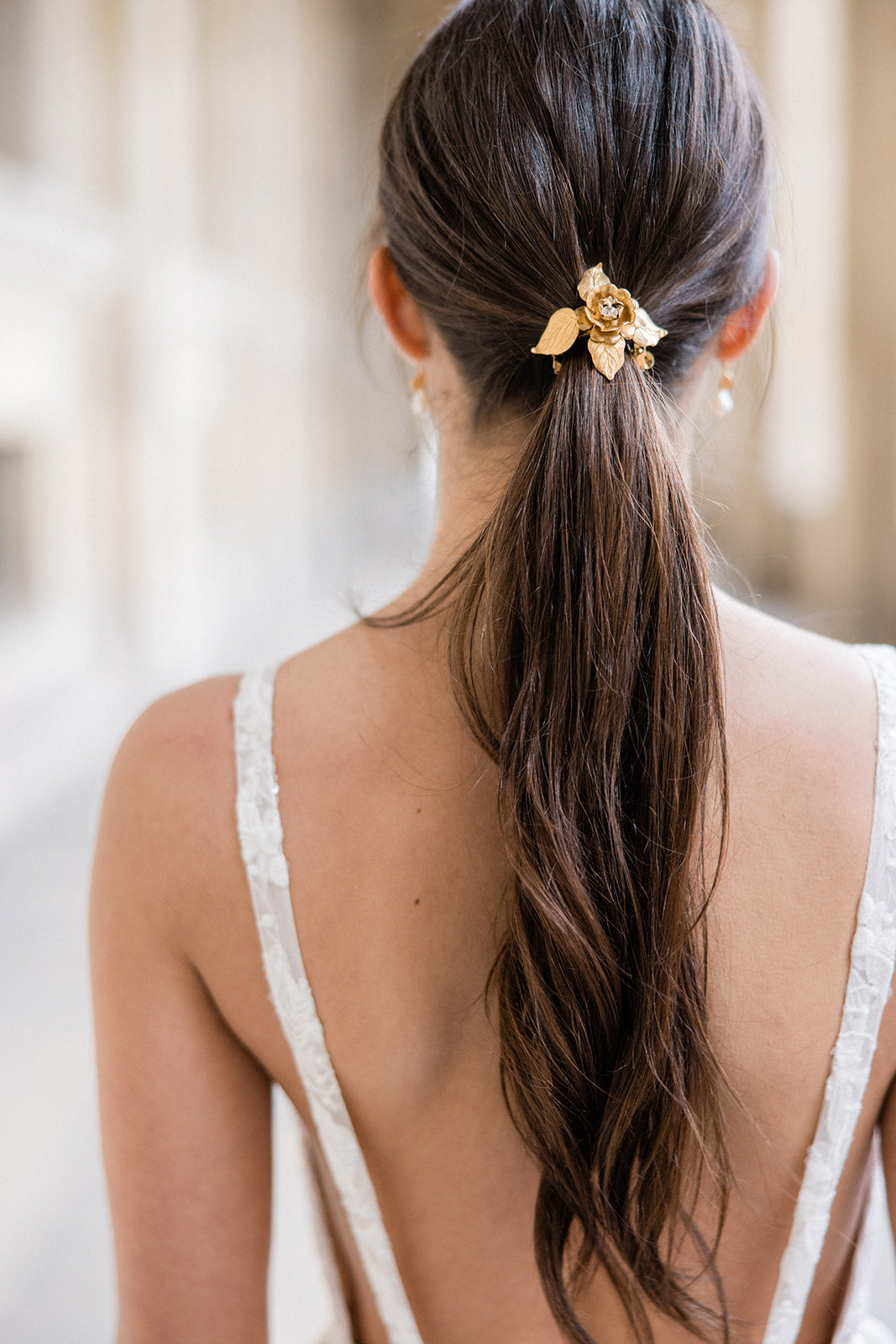 Mariée avec une queue-de-cheval basse accroché avec une barrette à fleur dorée