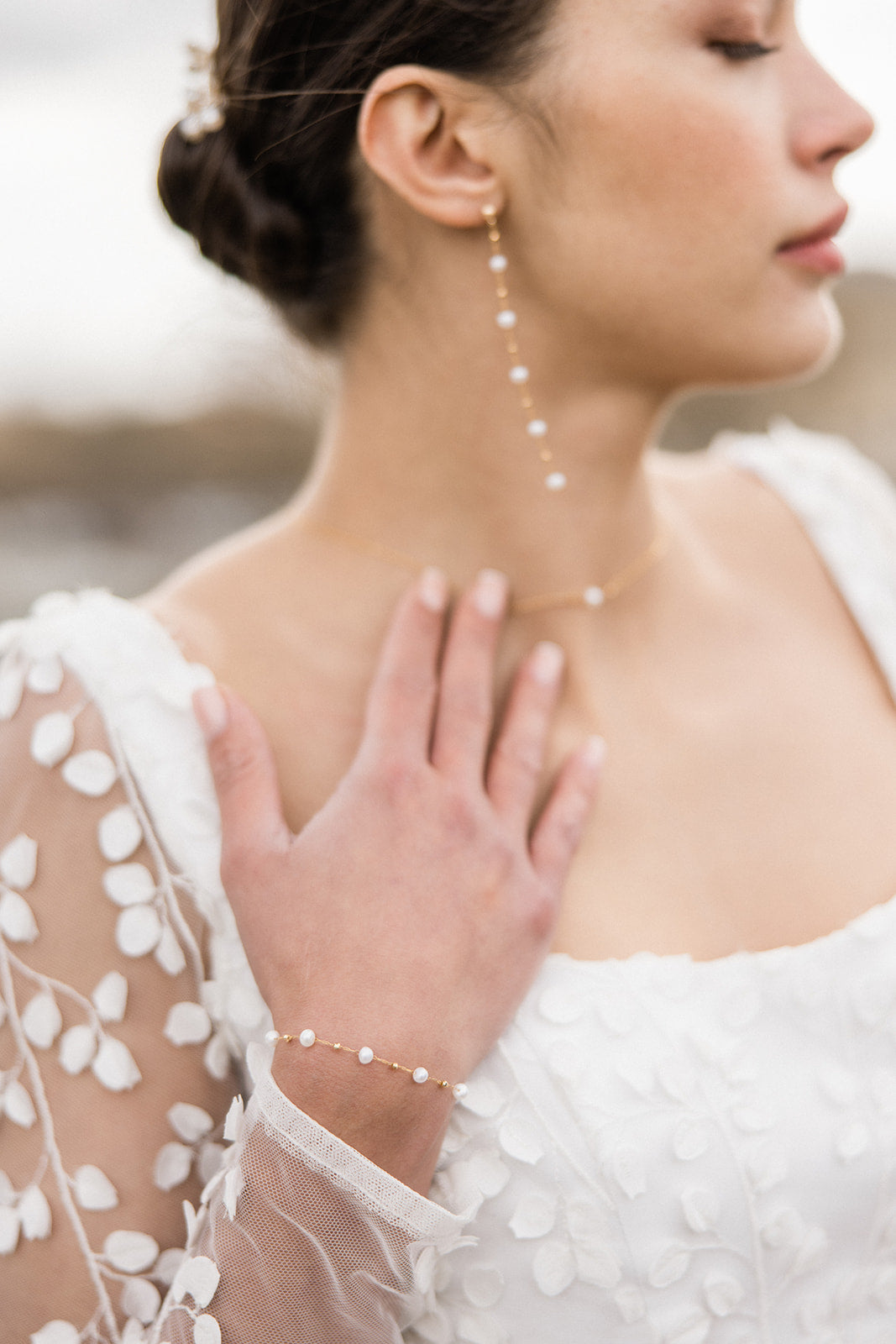 bracelet de mariage en perles naturelles avec une chaine en or porté par une mariée