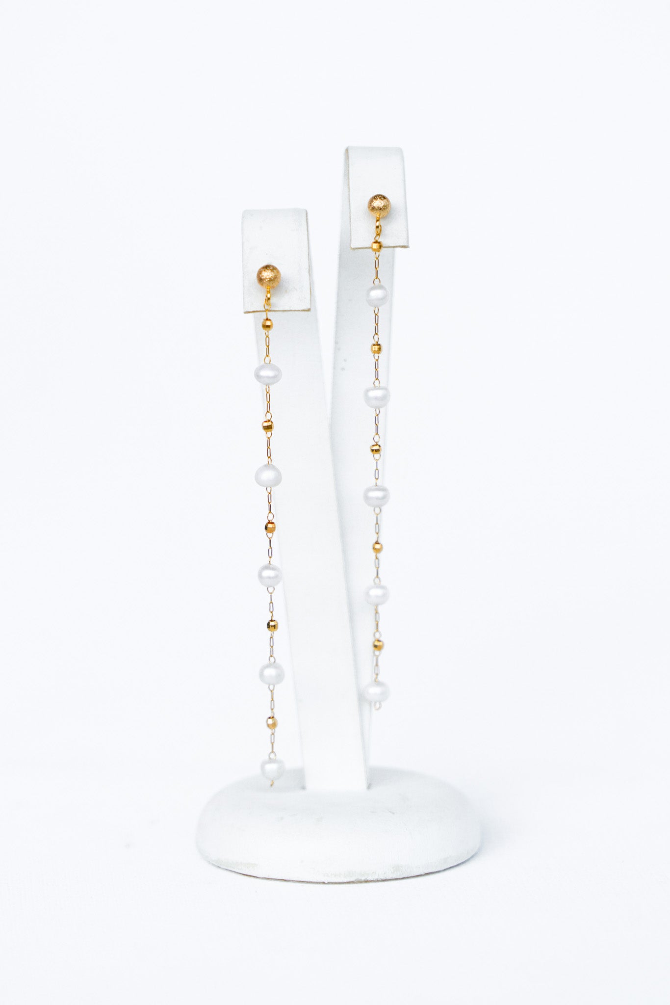 boucles d'oreilles en perles naturelles et bille en or sur un portant à bijou