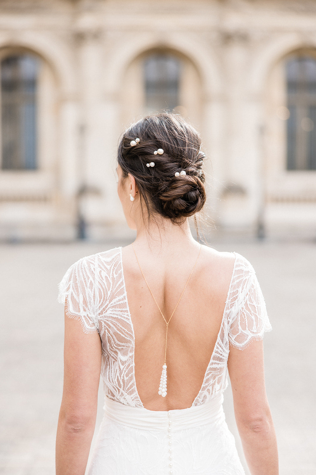 Coiffure de mariée moderne et élégant fait avec quatre pics à cheveux à perles et collier de dos en pompom de perles