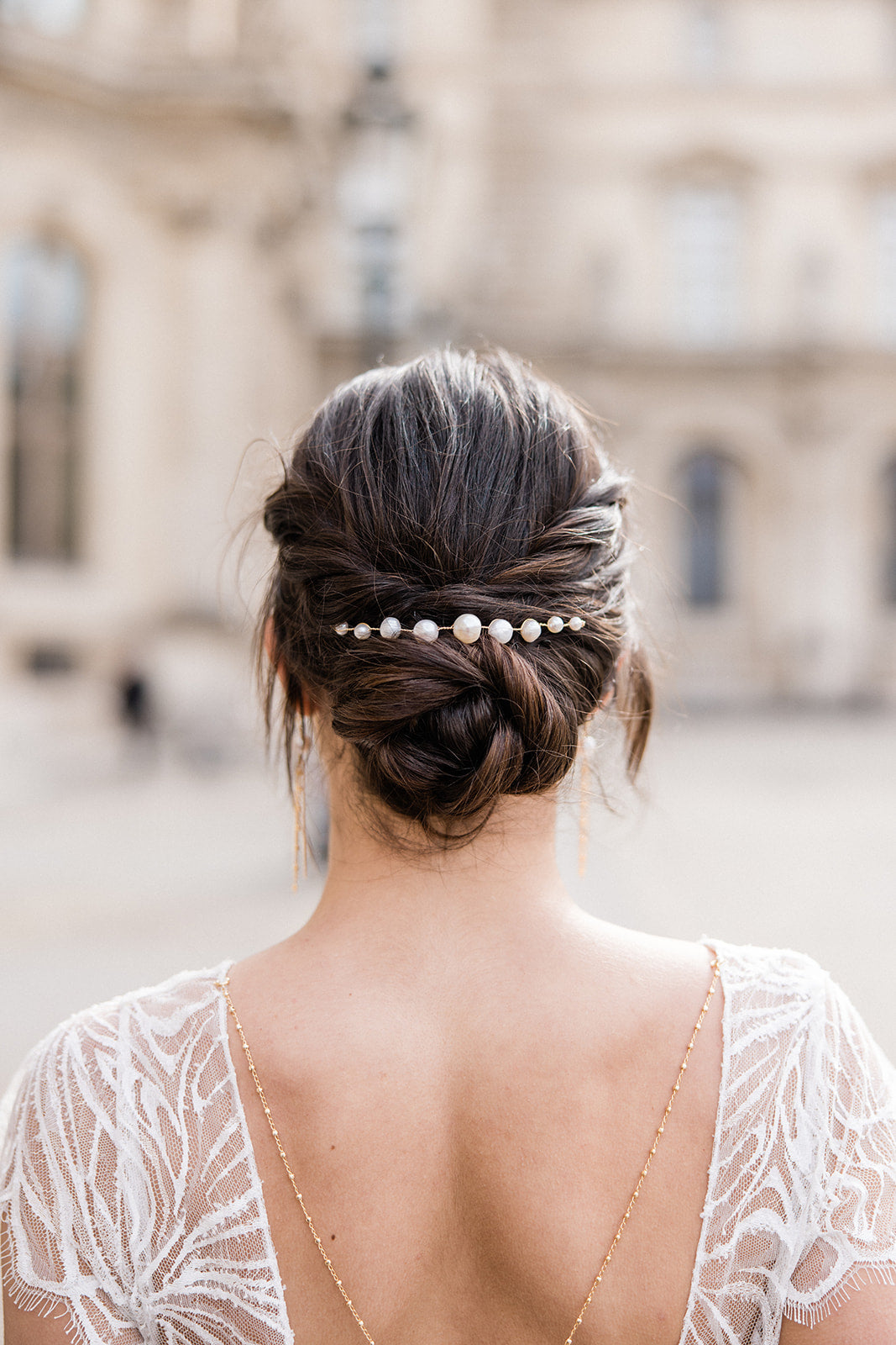 Mariée portant un pic à cheveux minimaliste de mariage à 9 perles naturelles, chignon bas et élégant, réalisé de manière soignée pour un look simple et raffiné.