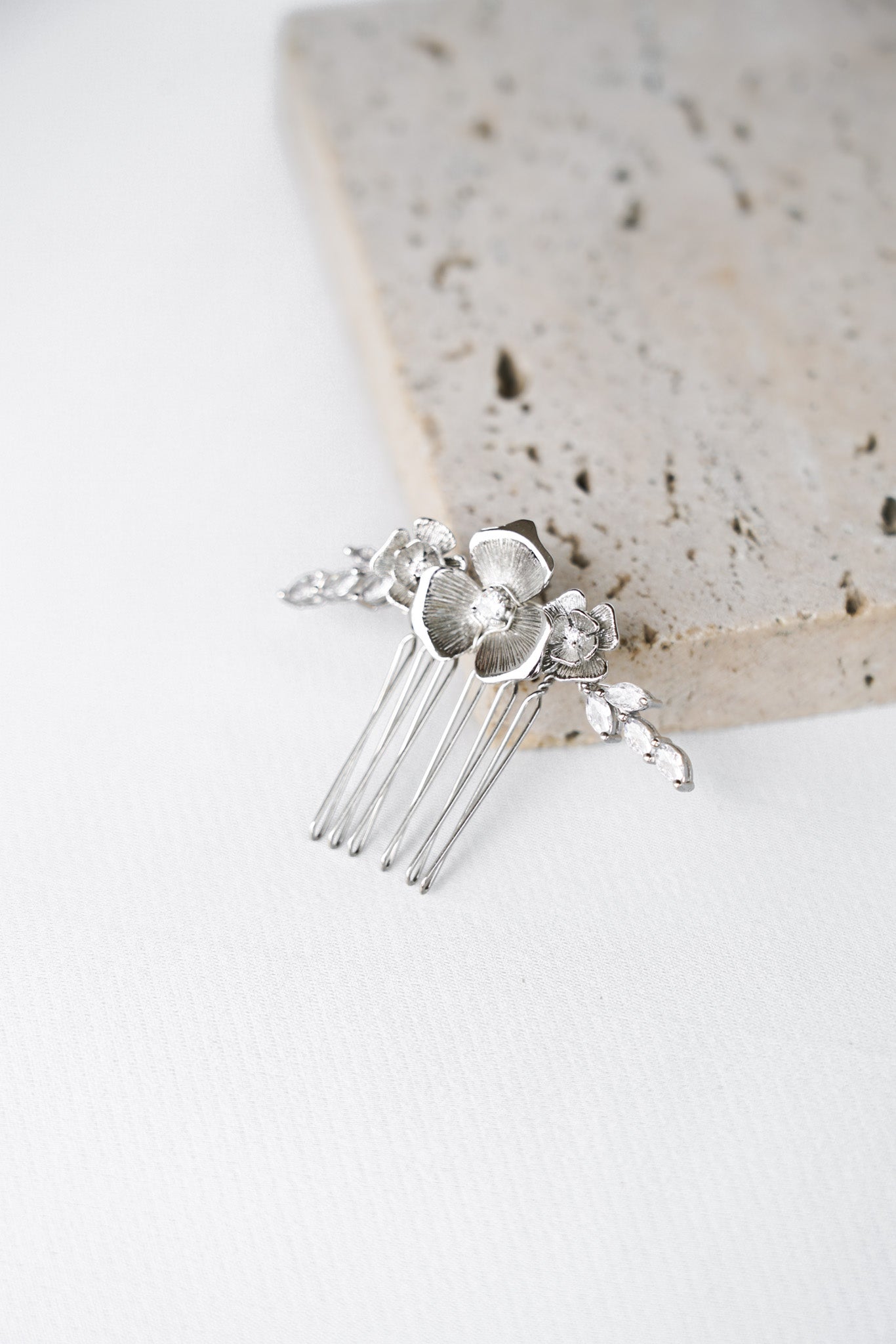 peigne mairage en argent avec un fleur et des cristaux posé sur une pièce de marbre