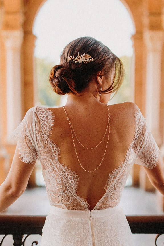 mariée avec un chignon bas portant un peigne floral et un collier de dos bohème