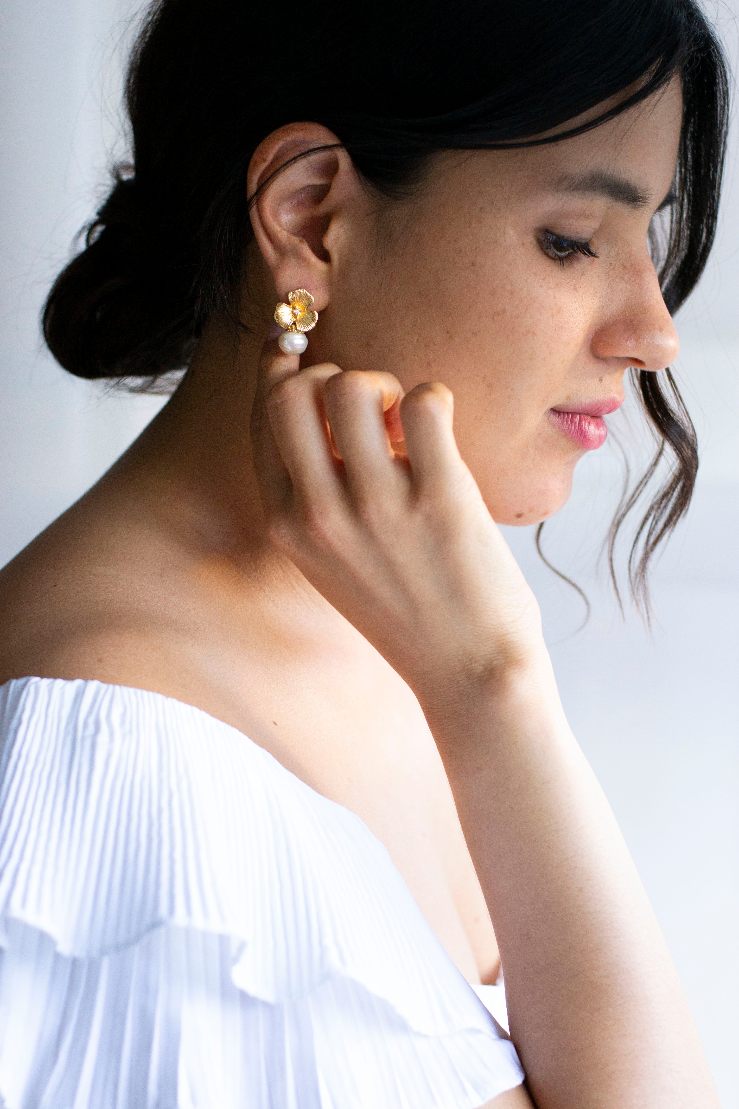 Mariée romantique avec boucles d'oreilles de mariage à fleurs or et perles