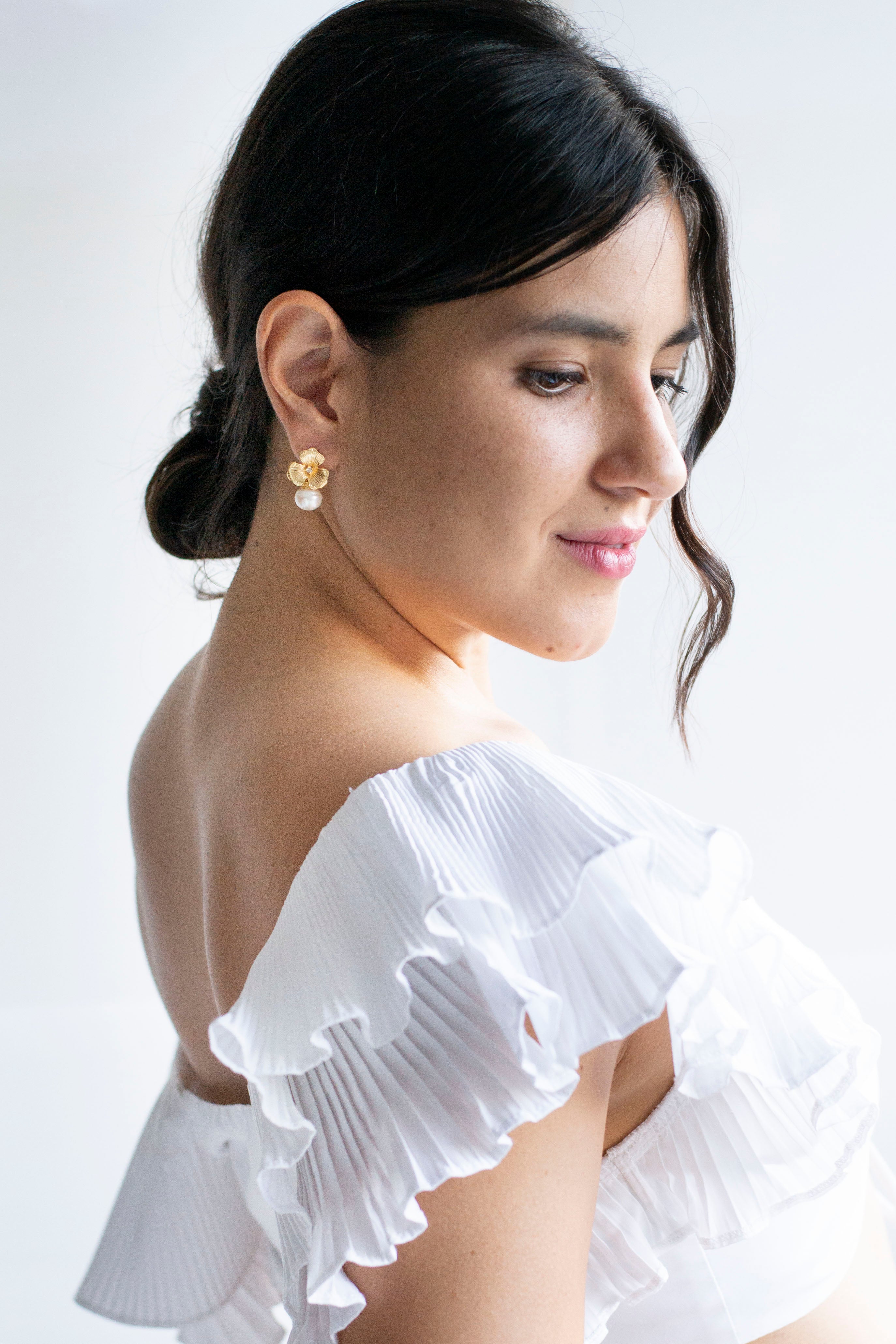 Mariée élégante et romantique portant des boucles d'oreilles à fleurs or et perles