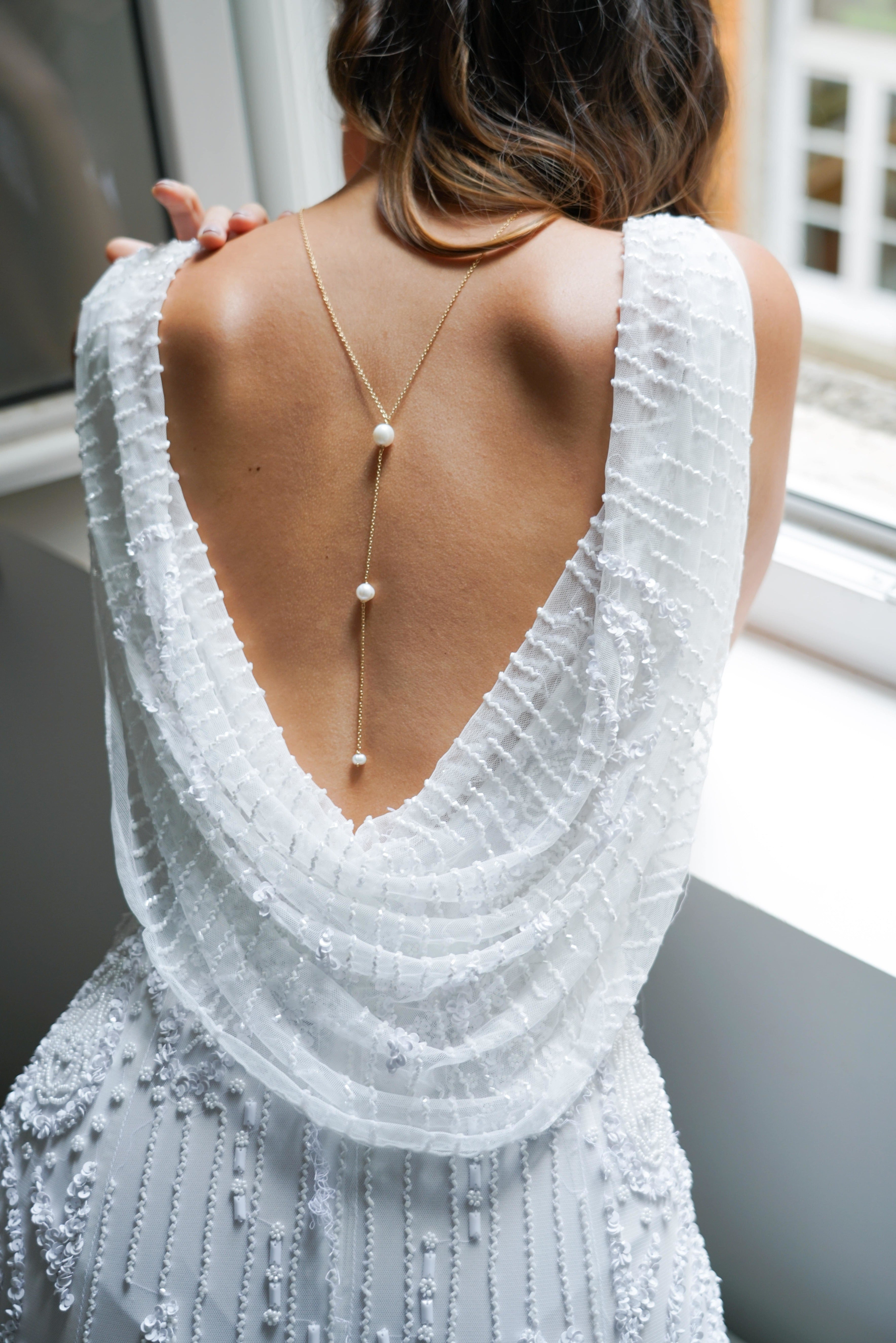 collier de dos pour mariage avec une chaine en or et 3 perle porté par la mariée