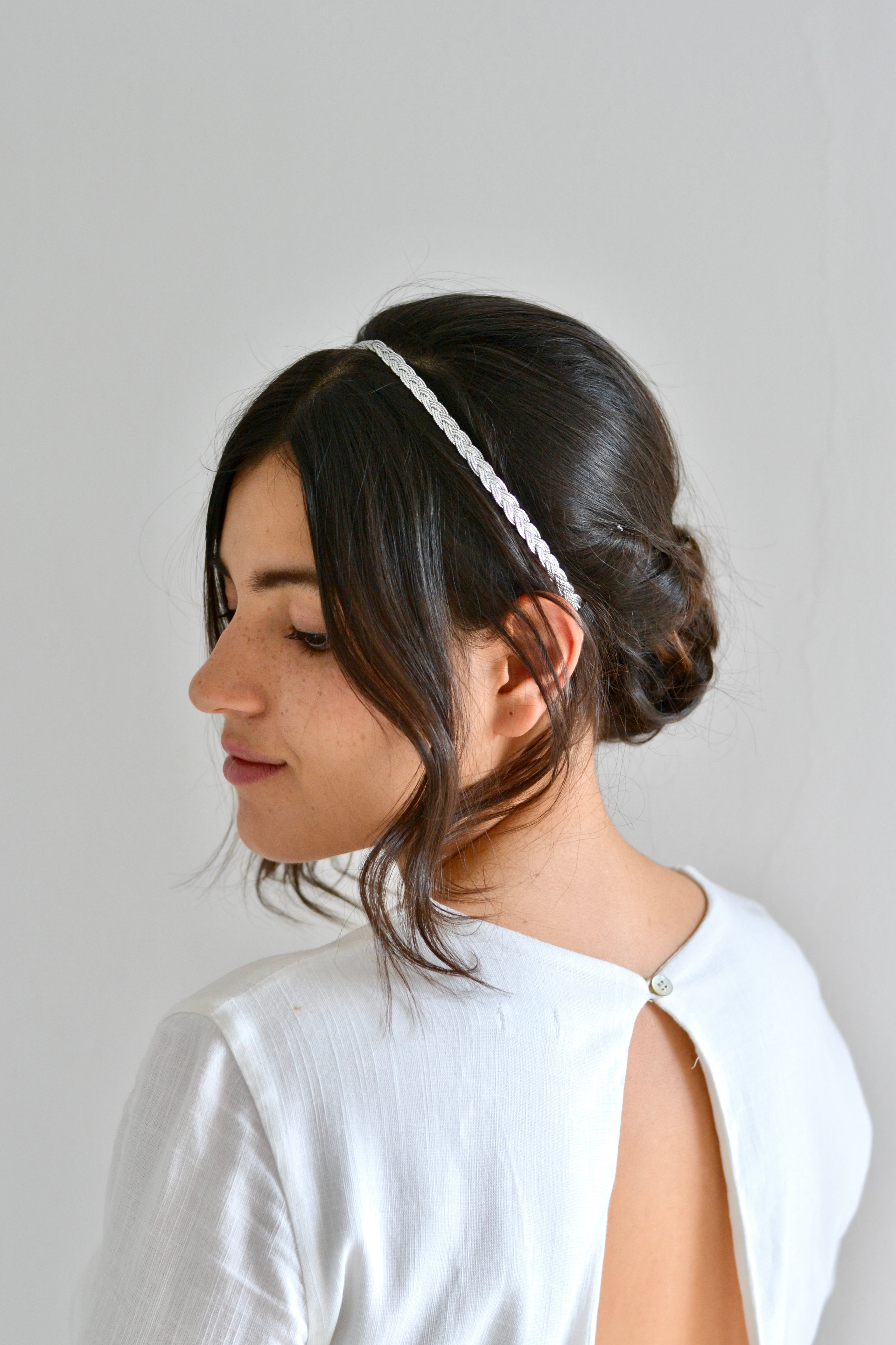demoiselle d'honneur portant un headband en argent en forme de tresse avec un chignon bas et une robe dos nu