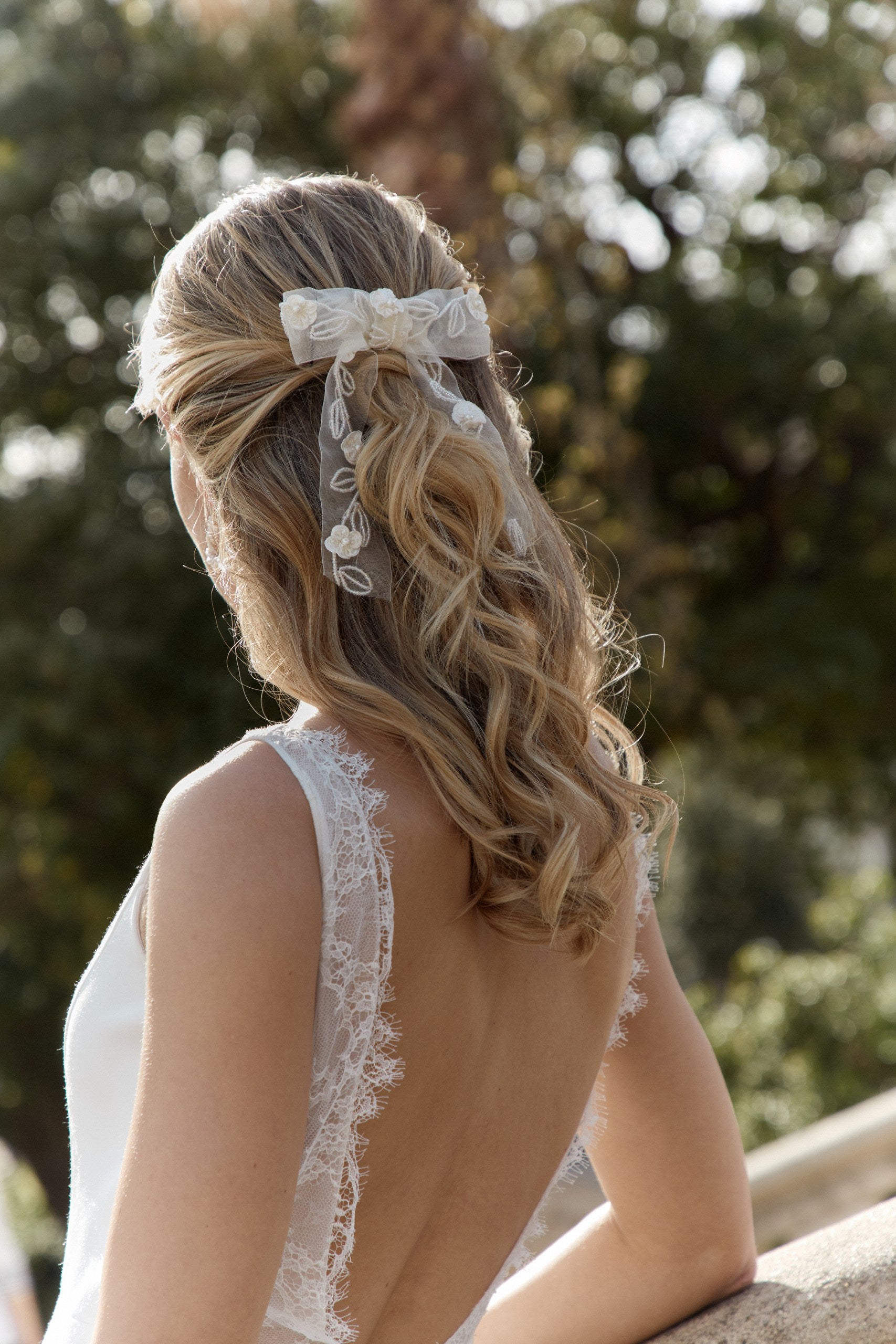 Femme au cheveux longs coiffé en une demi queue avec un noeud pour mariée