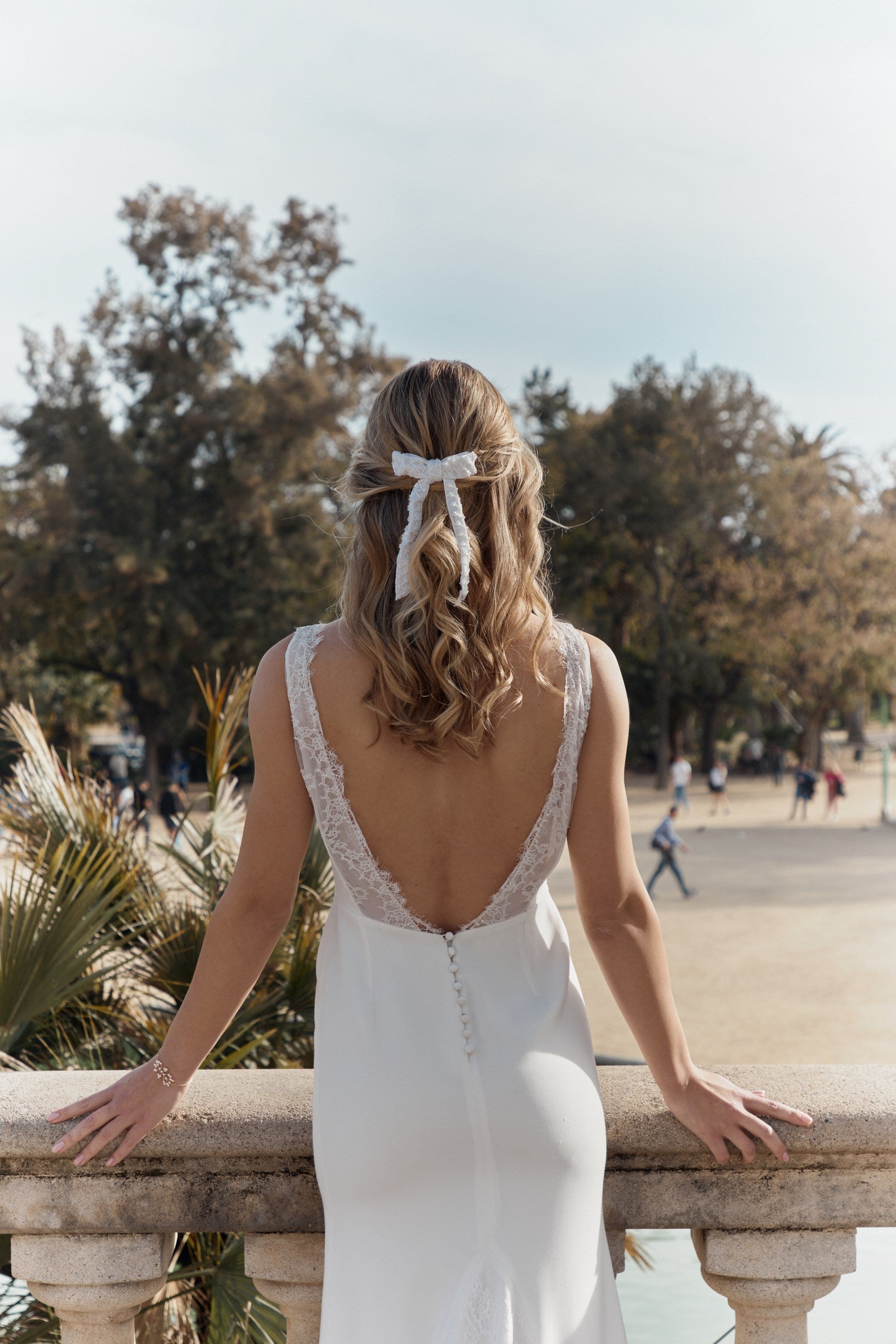 Femme avec une robe de mariée de dos portant un accessoire de cheveux type noeud