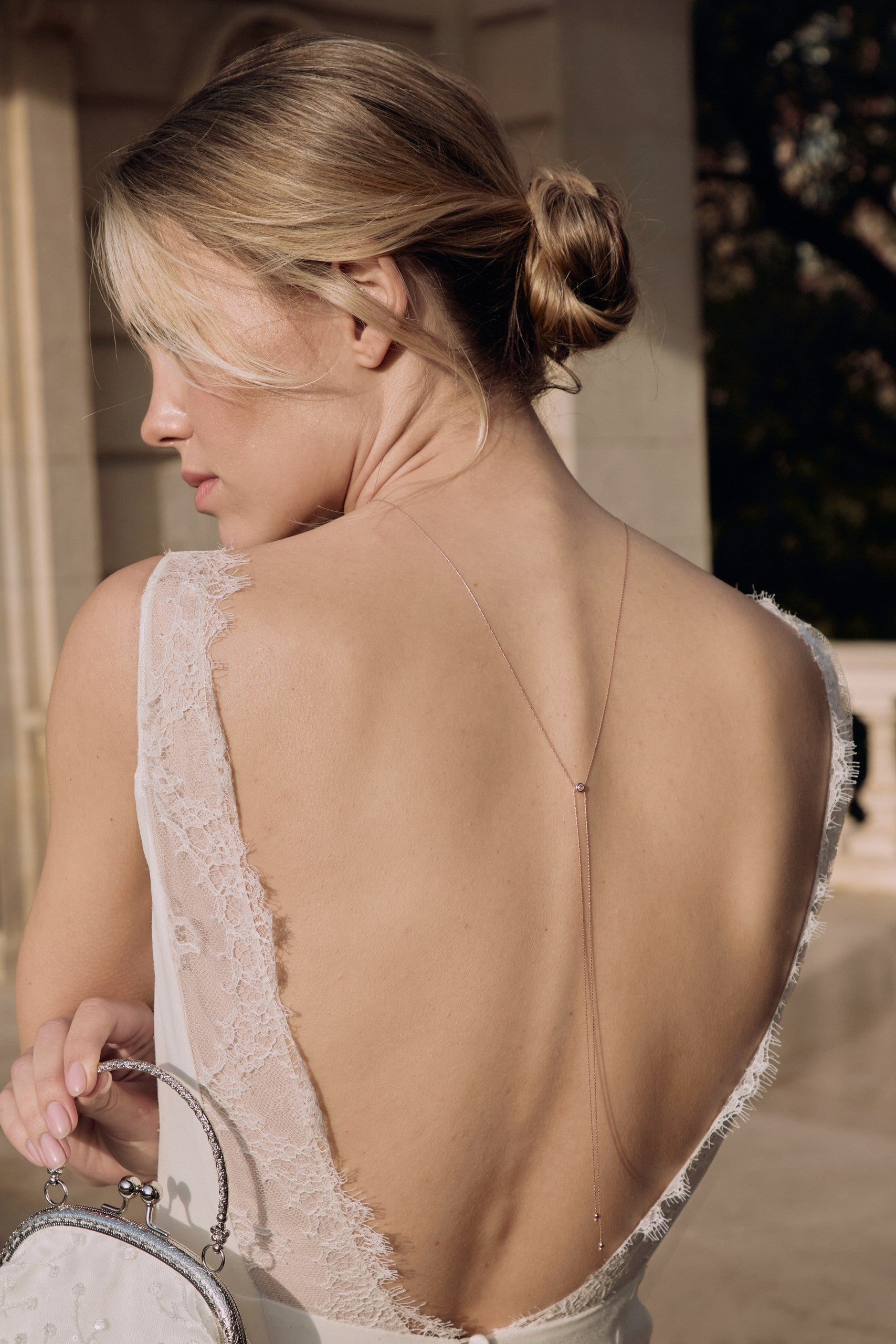 Mariée de dos avec une robe avec un grand décolleté de dos et un collier de dos minimaliste