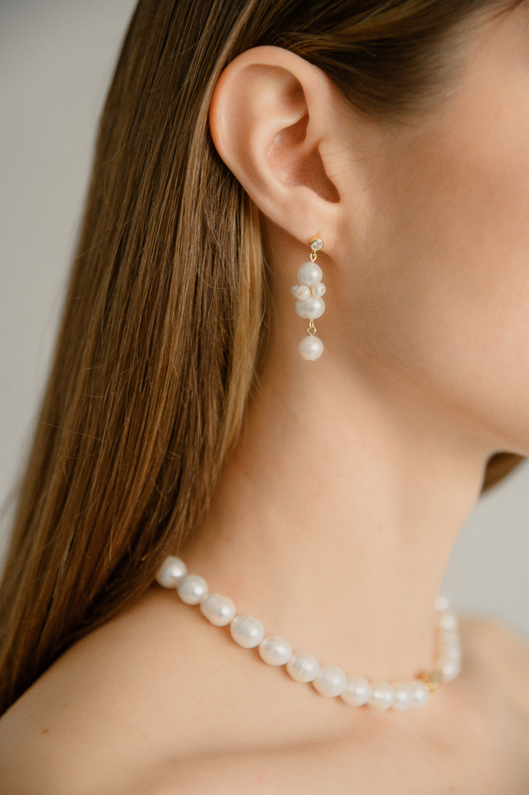 femme portant des bijoux dont des boucles d'oreilles et un collier en perles naturelles et en or