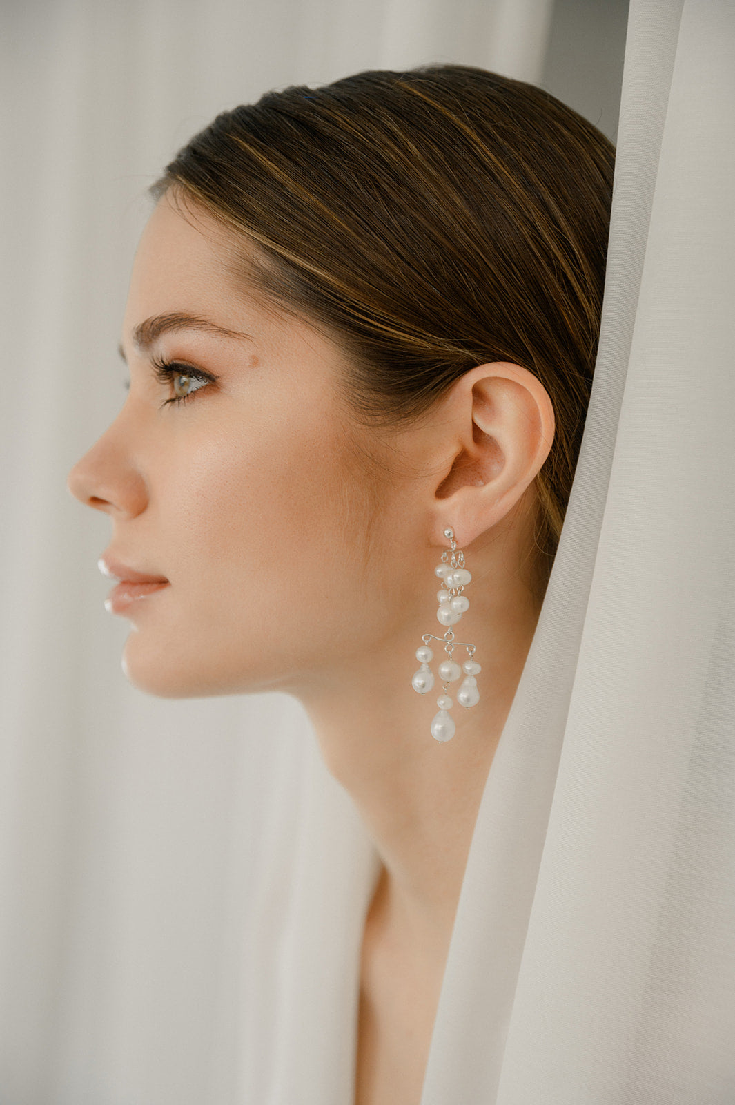 femme dans un studio de photographe portant des boucles d'oreilles pendentes en perles naturelles 