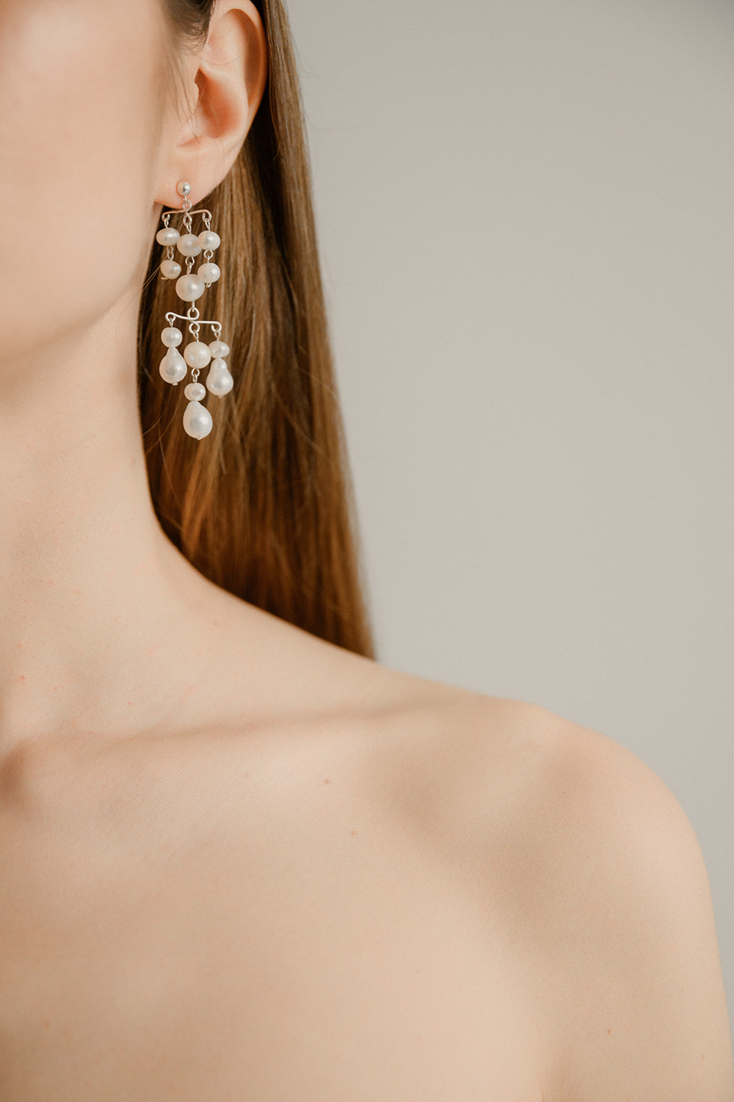 épaule d'une femme portant des boucles d'oreilles en perles naturelles et les cheveux dans son dos détachés 