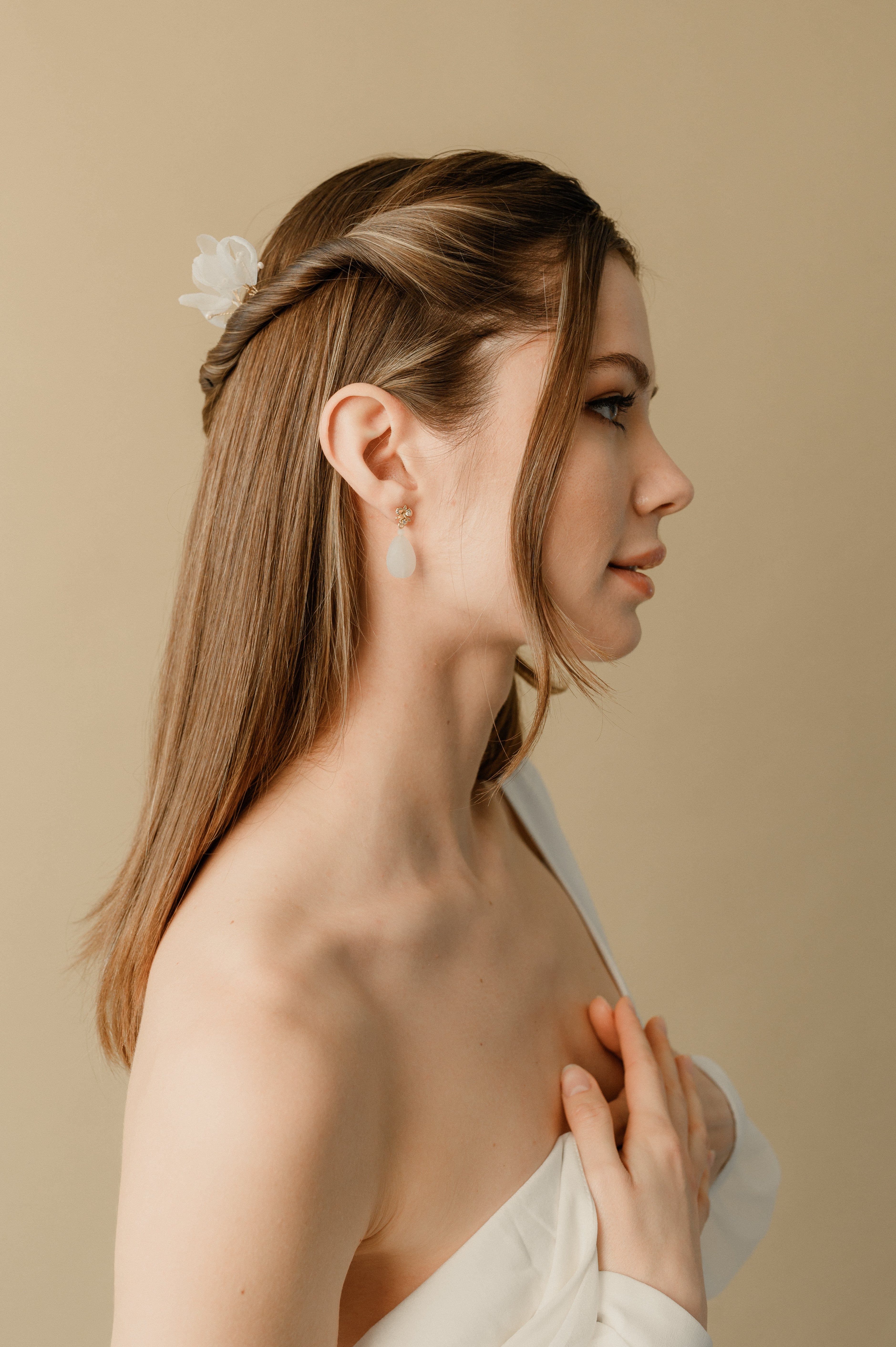 jeune femme portant une robe de mariée avec des boucles d'oreilles et une demi queue de cheval