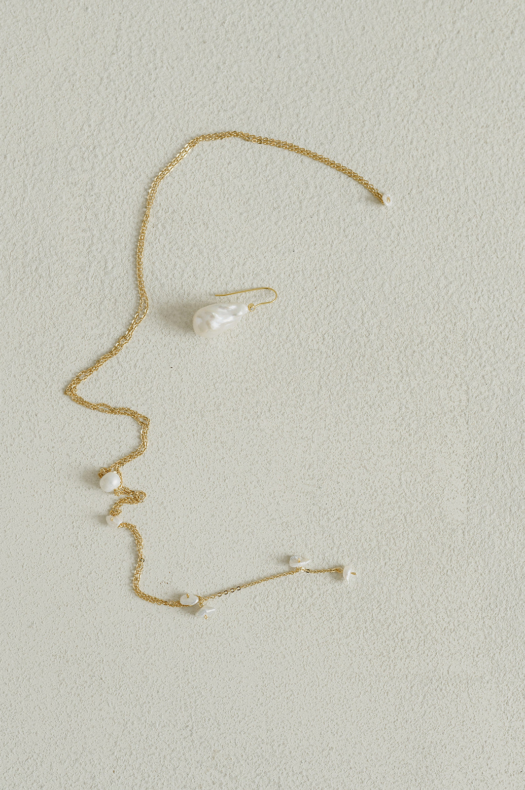 collier de dos et boucle d'oreille de mariage en perle naturelle posés sur une table blanche 