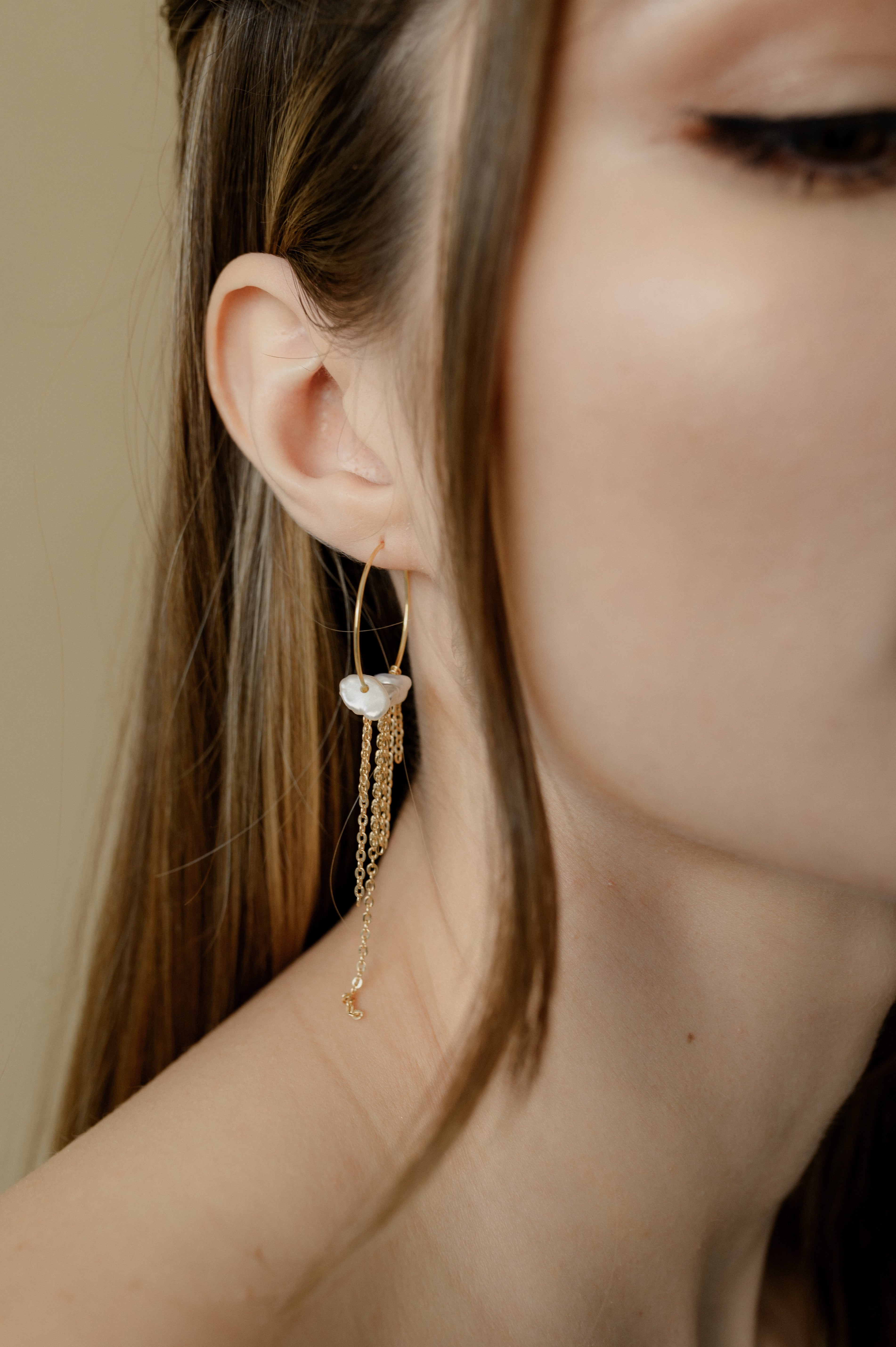 femme qui porte des boucles d'oreilles en forme de cercle avec des perles naturelles et des chaines pendantes