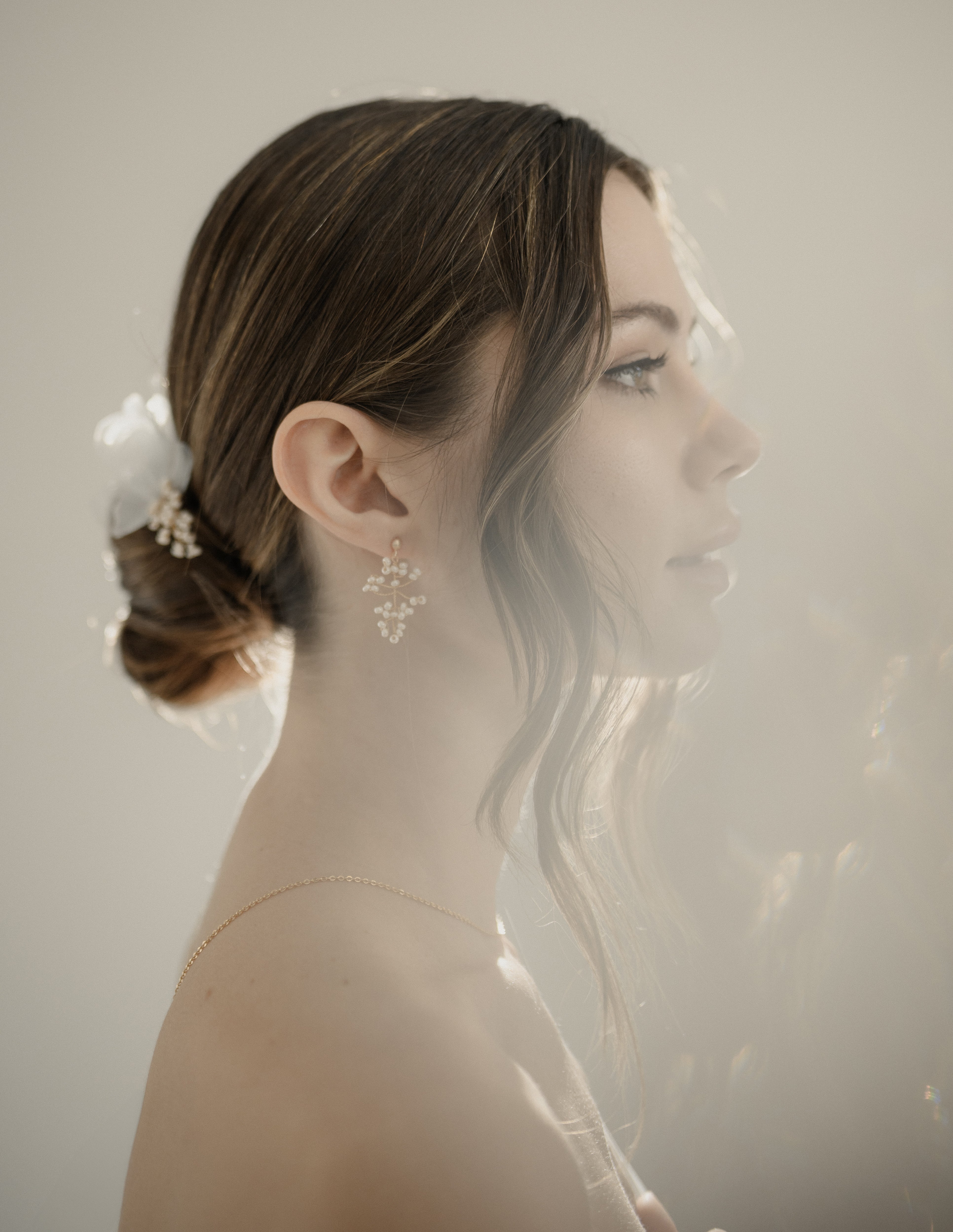 femme prise de profil portant une paire de boucles d'oreilles avec de la lumière à contre jour