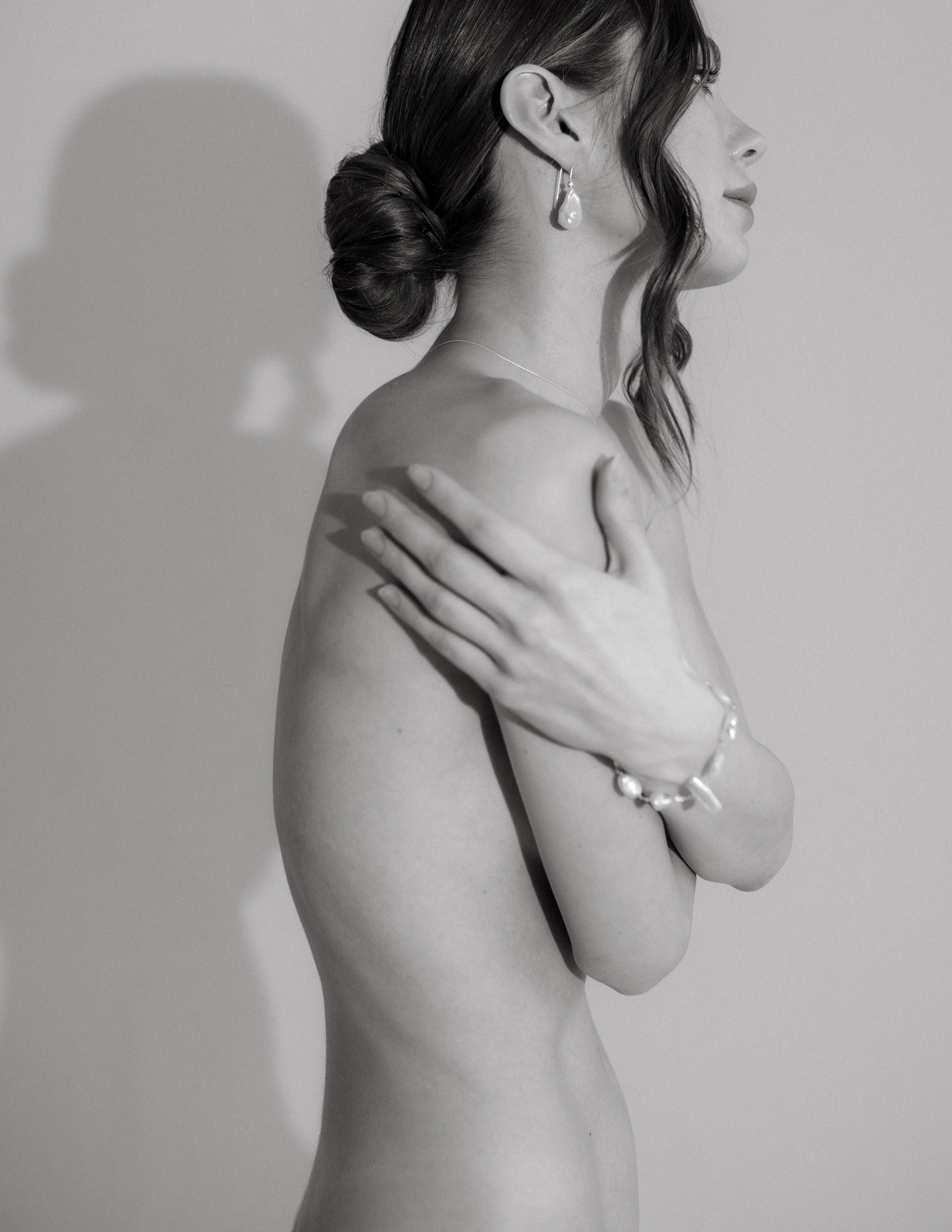 haut du corps d'une femme en noir et blanc qui porte u bracelet en perles naturelles baroque