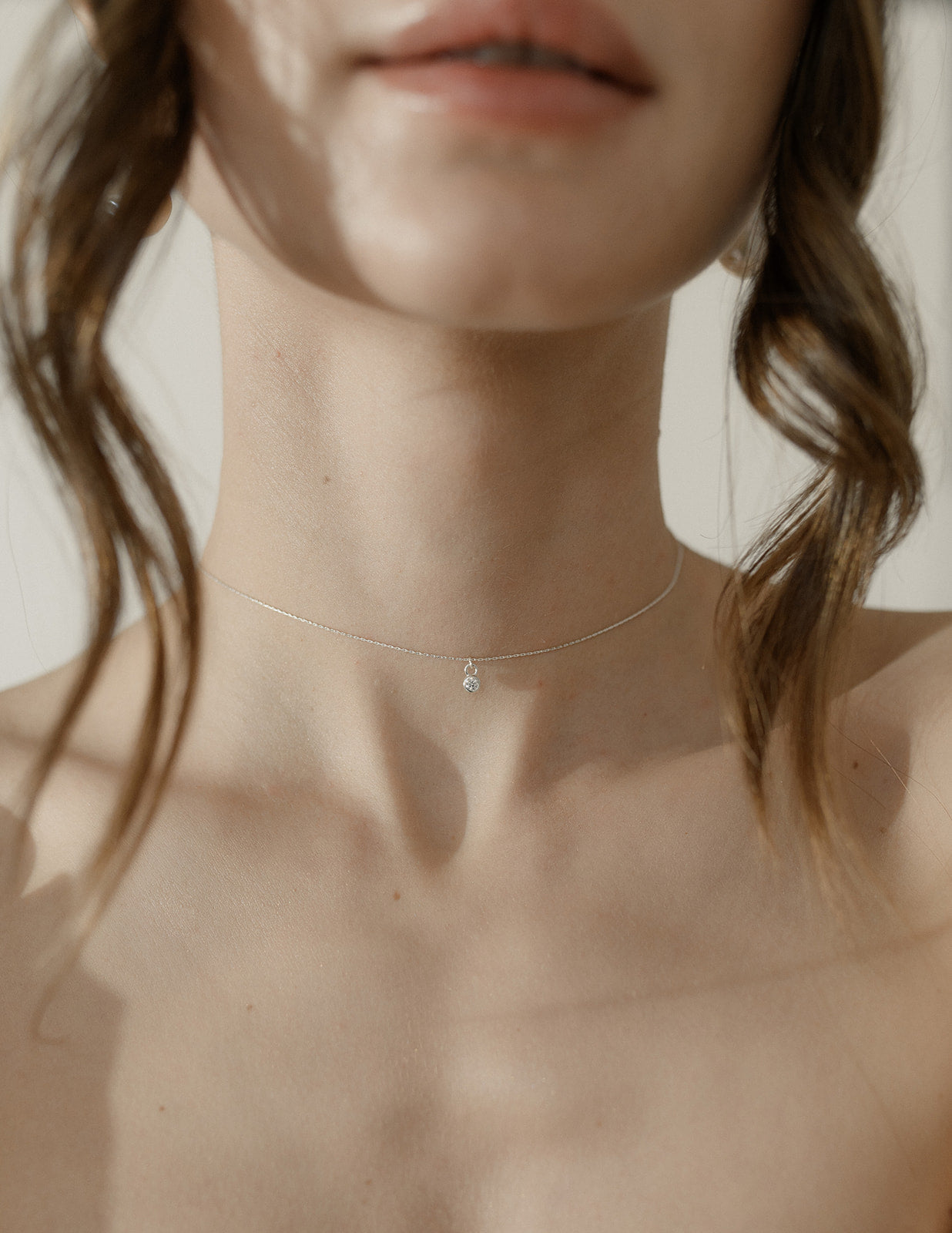 cou d'une femme portant un collier avec un pendentif en zircon avec ds cheveux dépassant 