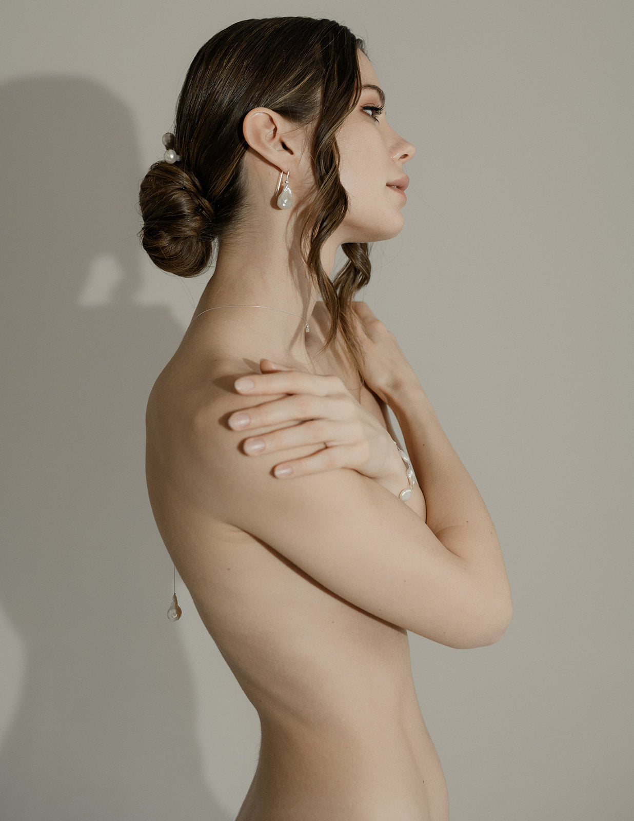 Femme nu de manière artistique avec les cheveux attachés mettant en avant une parure de bijoux de mariage baroque