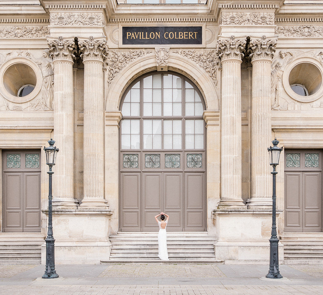 photo du shooting de la collection 2023 à Paris d'Atelier Lilac au Pavillon Cobert avec la mariée devant le pavillon portant sa robe blanche du mariage