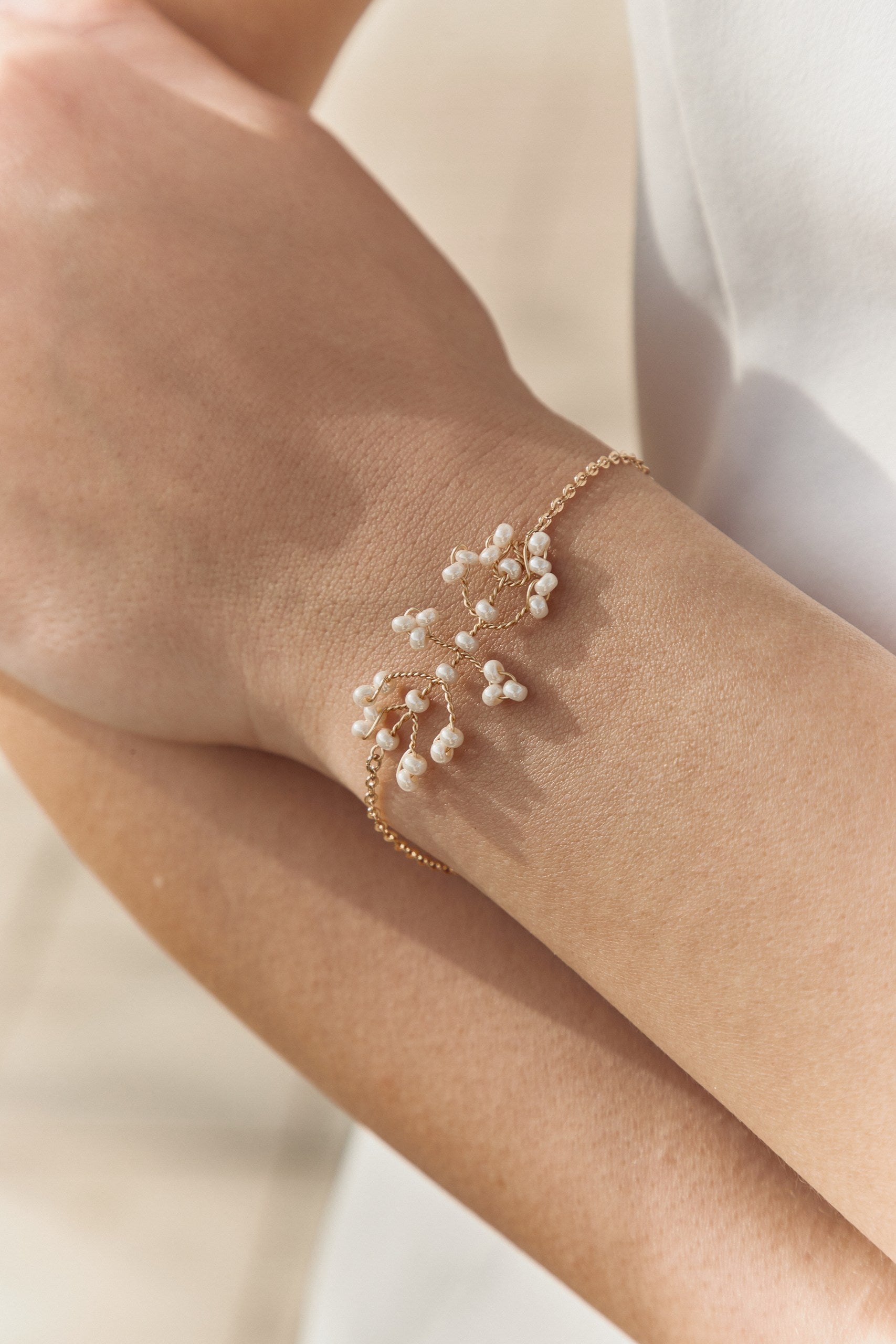 gros zoom sur le bras d'une jeune femme portant un bracelet de mariage en perles rocailles