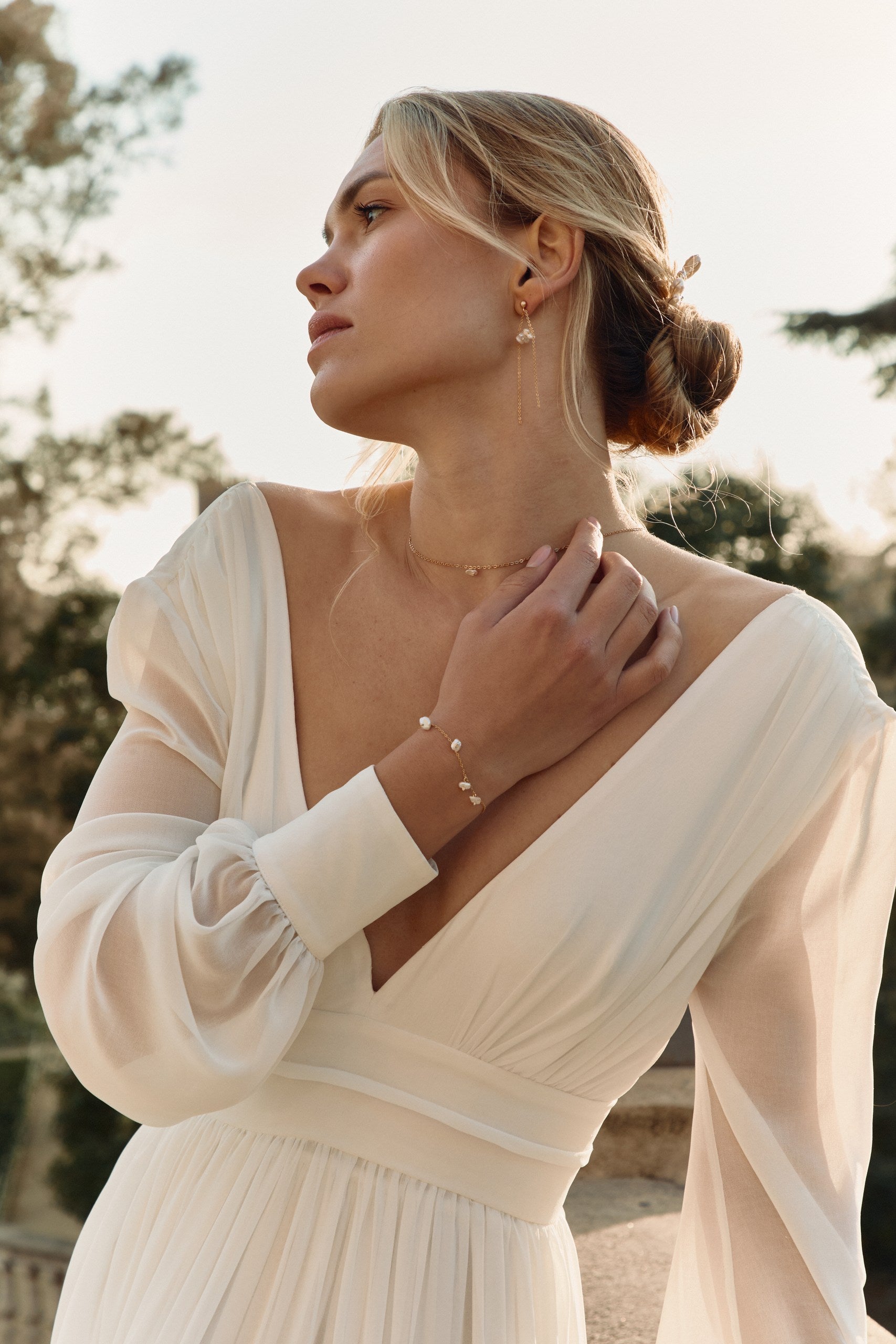 Femme avec une robe de mariée se touchant le coup avec sa main montrant son bracelet à perles irrégulières
