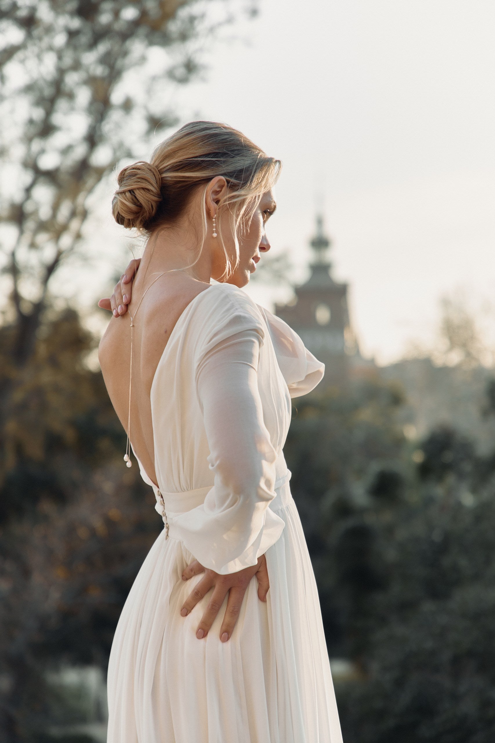 Mariée de profil en robe avec décolleté de dos et collier de dos bohème 