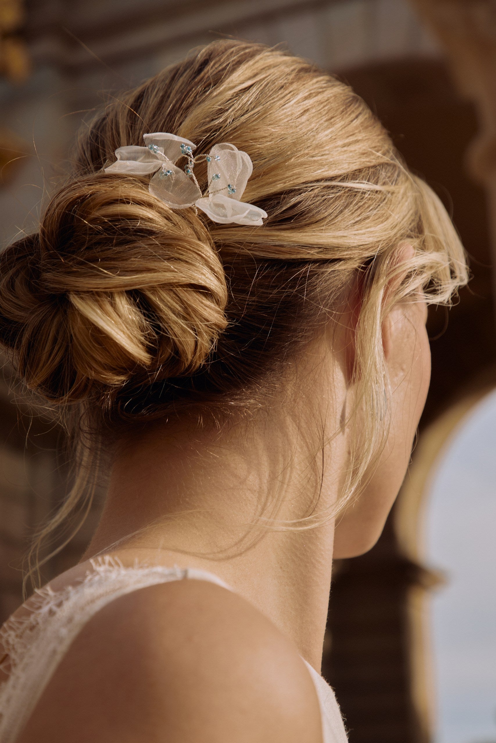 gros plan sur le chignon d'une femme blonde avec des accessoires de cheveux en pics à chignon bleu et blanc habillée en robe de mariée et 