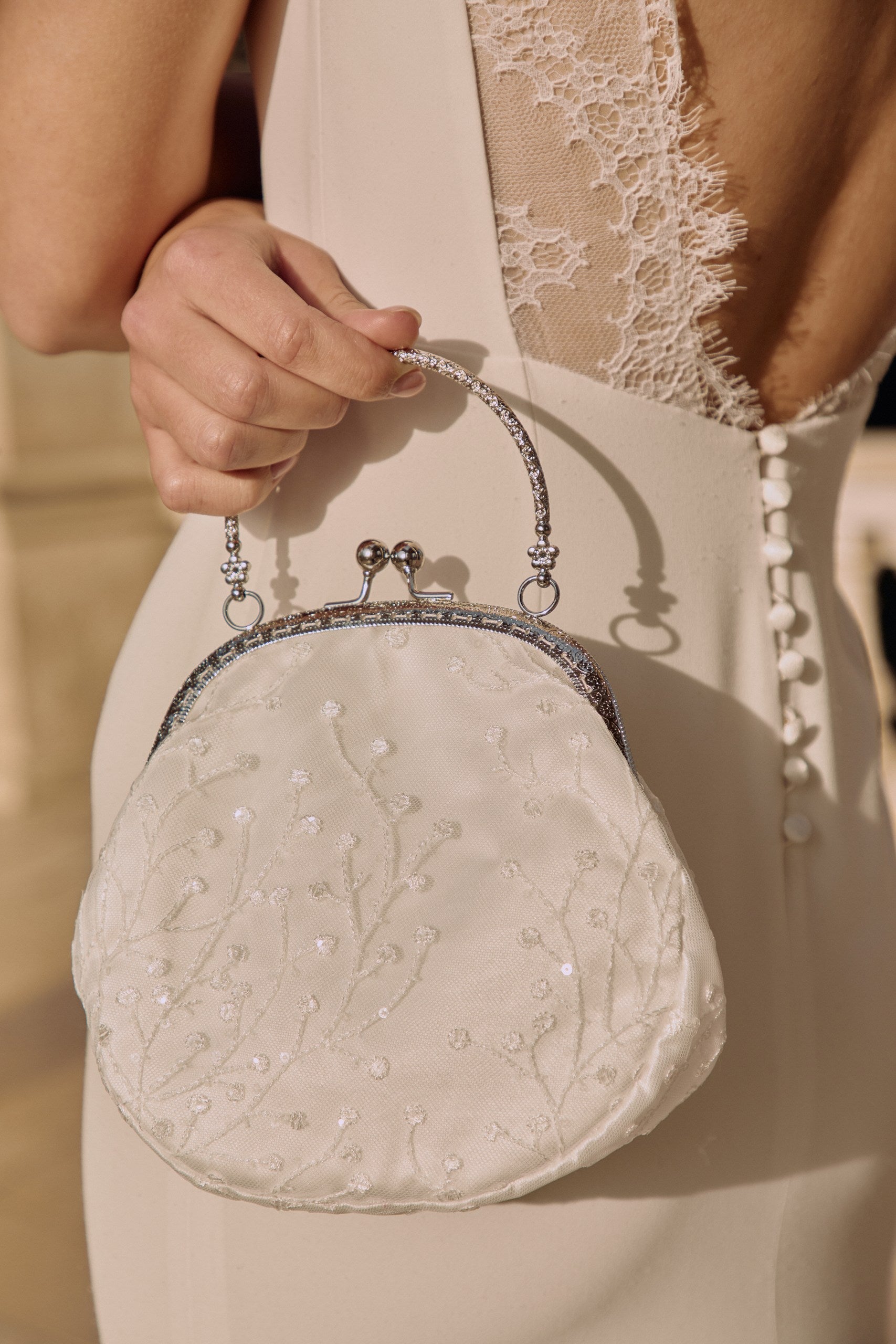 Gros plan sur un sac blanc à sequin avec un style vintage porté par une mariée en robe