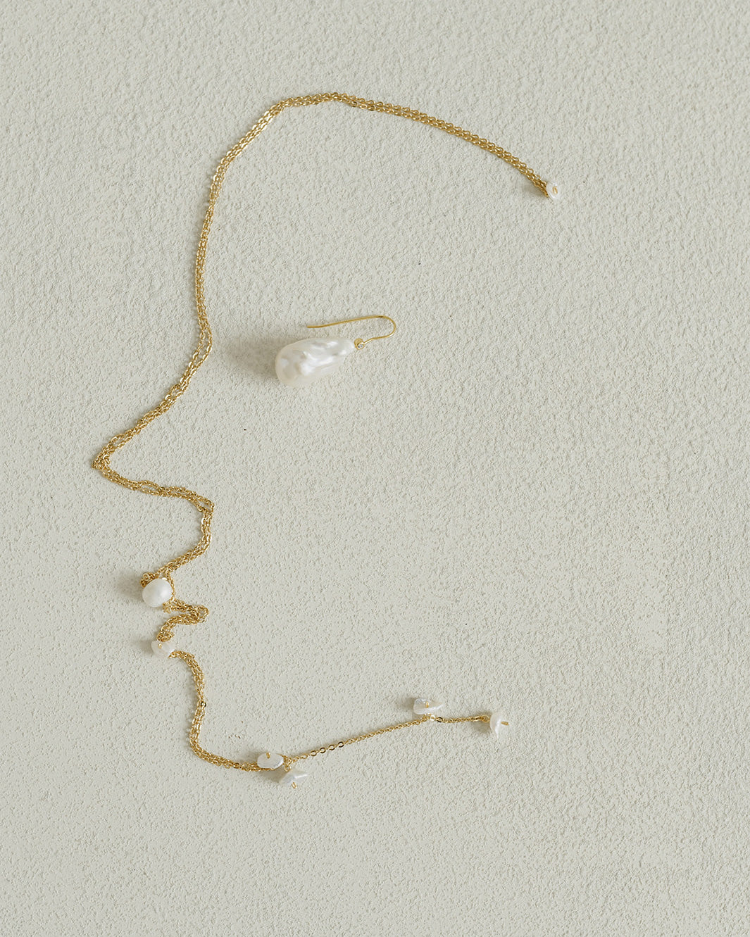 photo artistique de bijoux de mariage en chaine et perle naturelles sur un fond blanc 