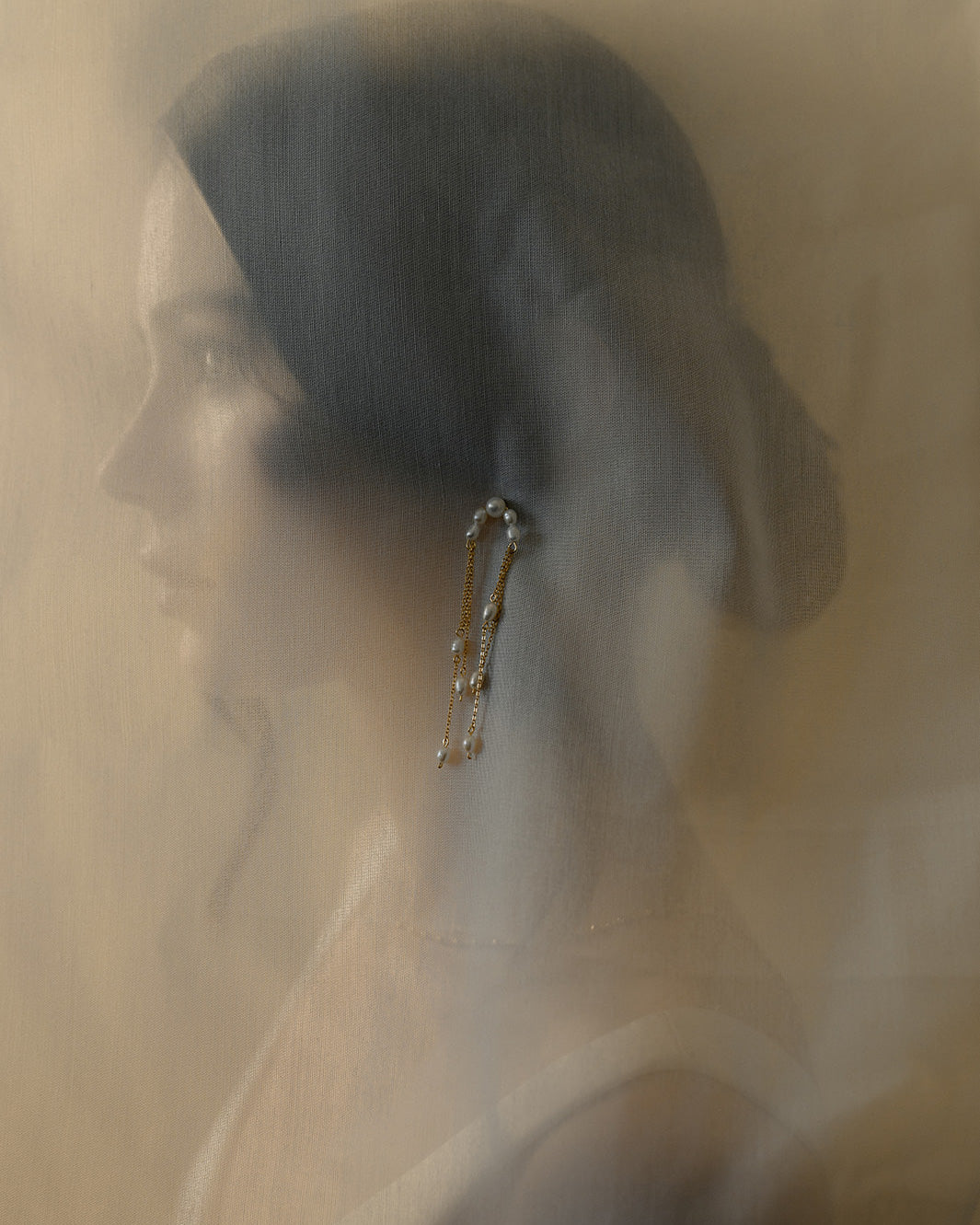 photo artistique d'une femme portant une boucle d'oreille sur un voile en tulle