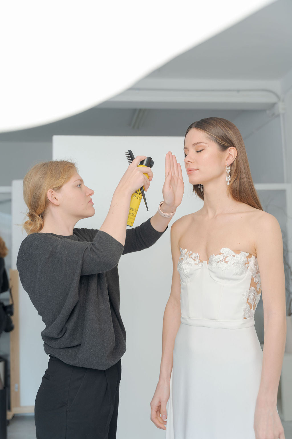 Photo prise lors d'un shooting photo de la mariée entrain de se faire coiffer par la maquilleuse coiffeuse de son mariage