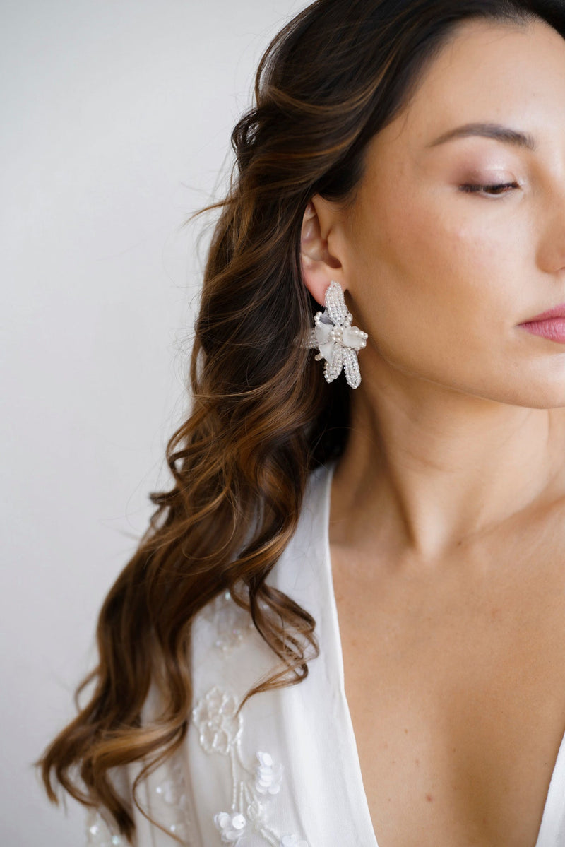 Mariée portant des boucles d'oreilles pendantes en forme de fleurs faite des pleins de petites perles rocailles blanches