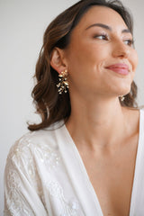 Mariée portant des boucles d'oreilles pendantes de fleurs et feuillages dorés avec des petites perles rocaillles