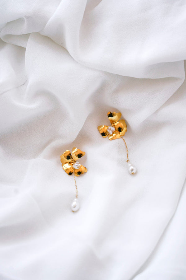 Boucles d'oreilles pendantes en forme de fleurs avec des pétales or et des petites perles naturelle qui pendent au bout d'une chaine