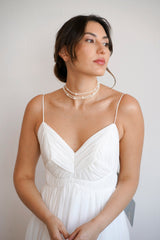 Mariée avec un chignon de mariage bohème portant un collier ras-le-cou à trois rangées en perles blanches