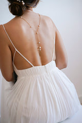 Mariée de dos portant un collier de dos doré à perles mis en valeur par le grand décolleté de dos de sa robe de mariée