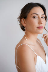 Mariée portant des boucles d'oreilles pendantes à perles et chaînes dorées
