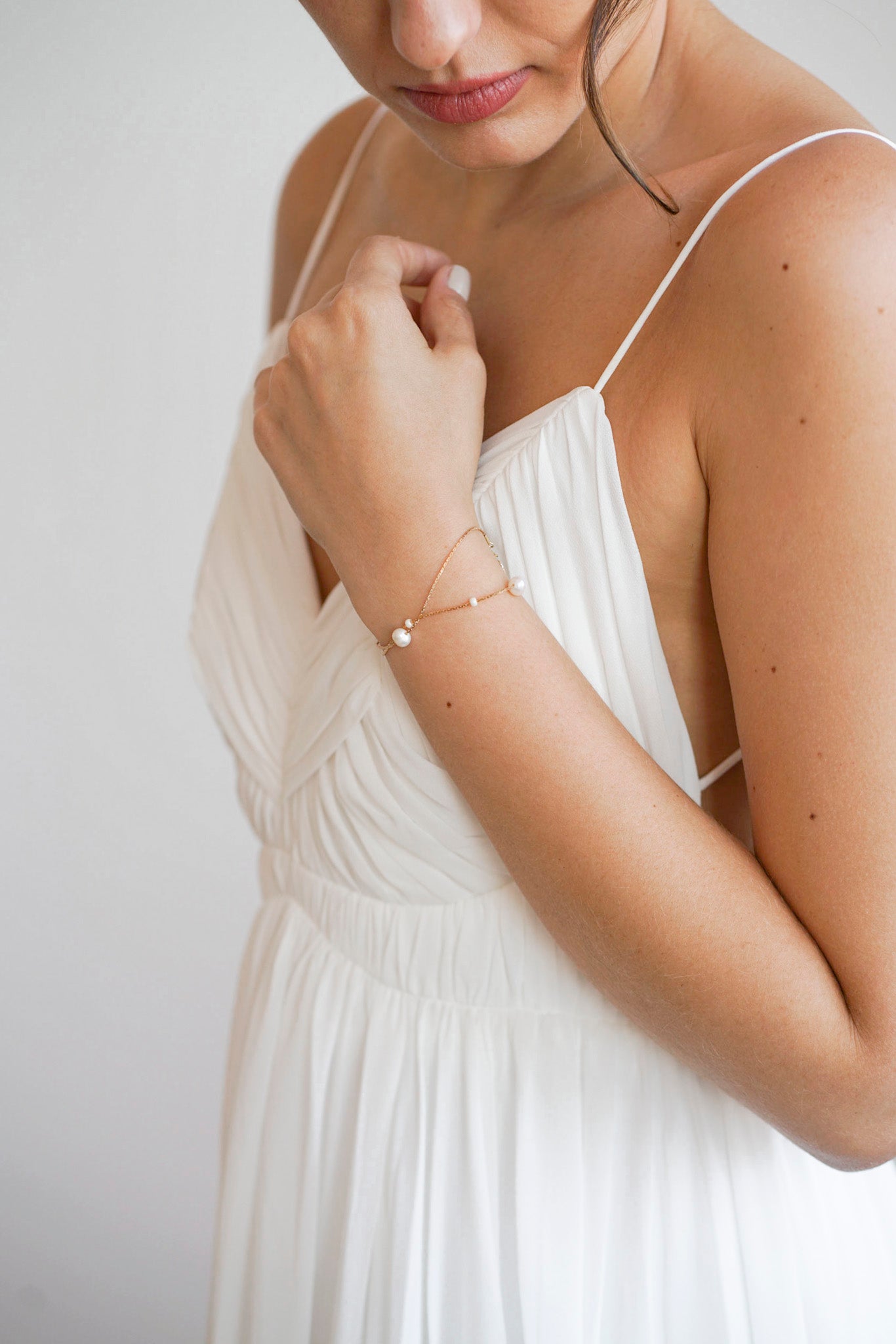 Mariée portant un bracelet à double chaines croisée parsemées de perles blanches