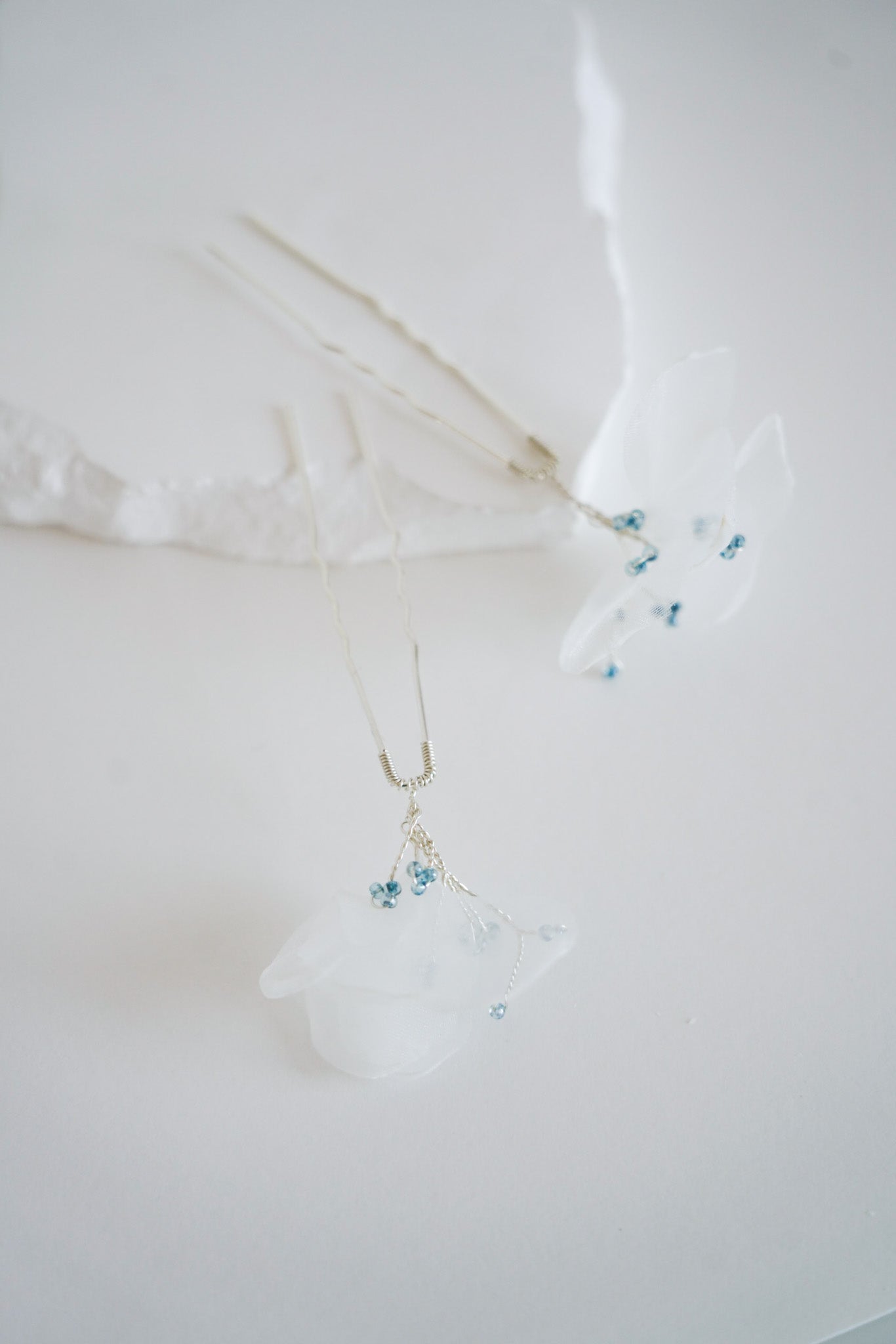 accessoires de cheveux pour mariée fabriqué avec un pic à chignon argenté, des perles rocailles bleu et du tulle blance