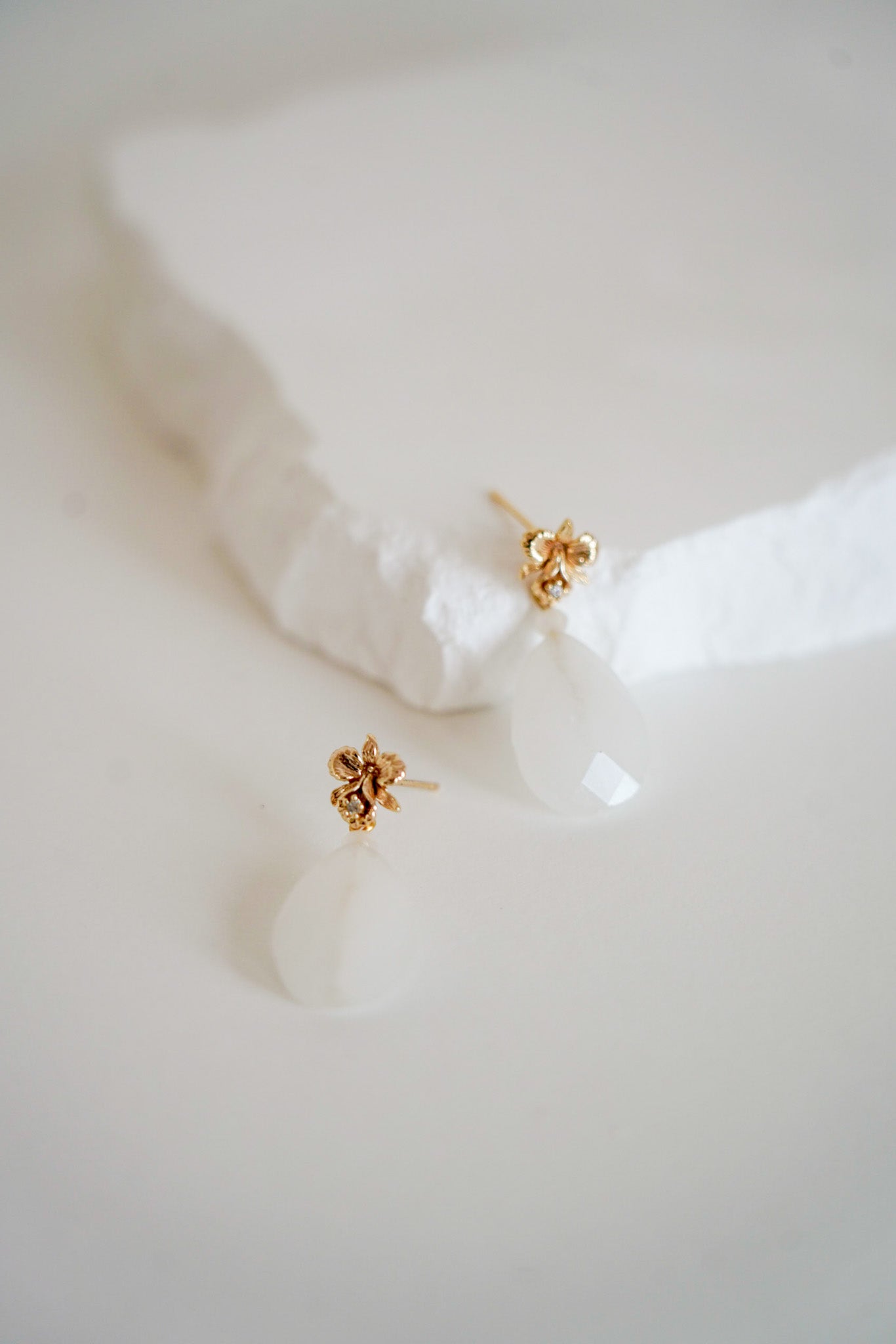 paire de boucles d'oreilles faite pour une mariée bohème avec une pierre naturelle blanche et une attache en forme de fleurs