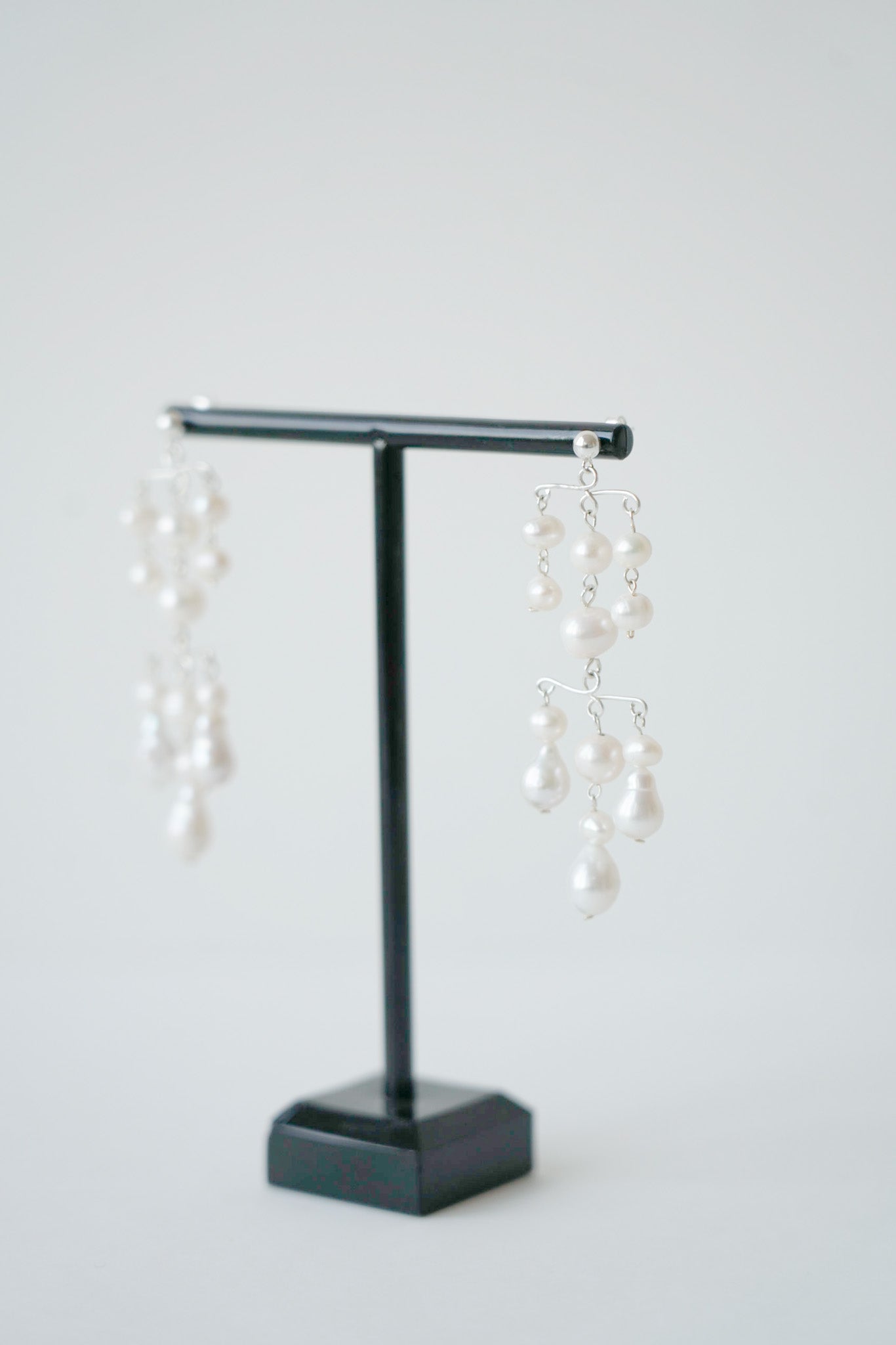 des boucles d'oreilles mariage bohème à étage de perles naturelles sur un portant à bijoux noir